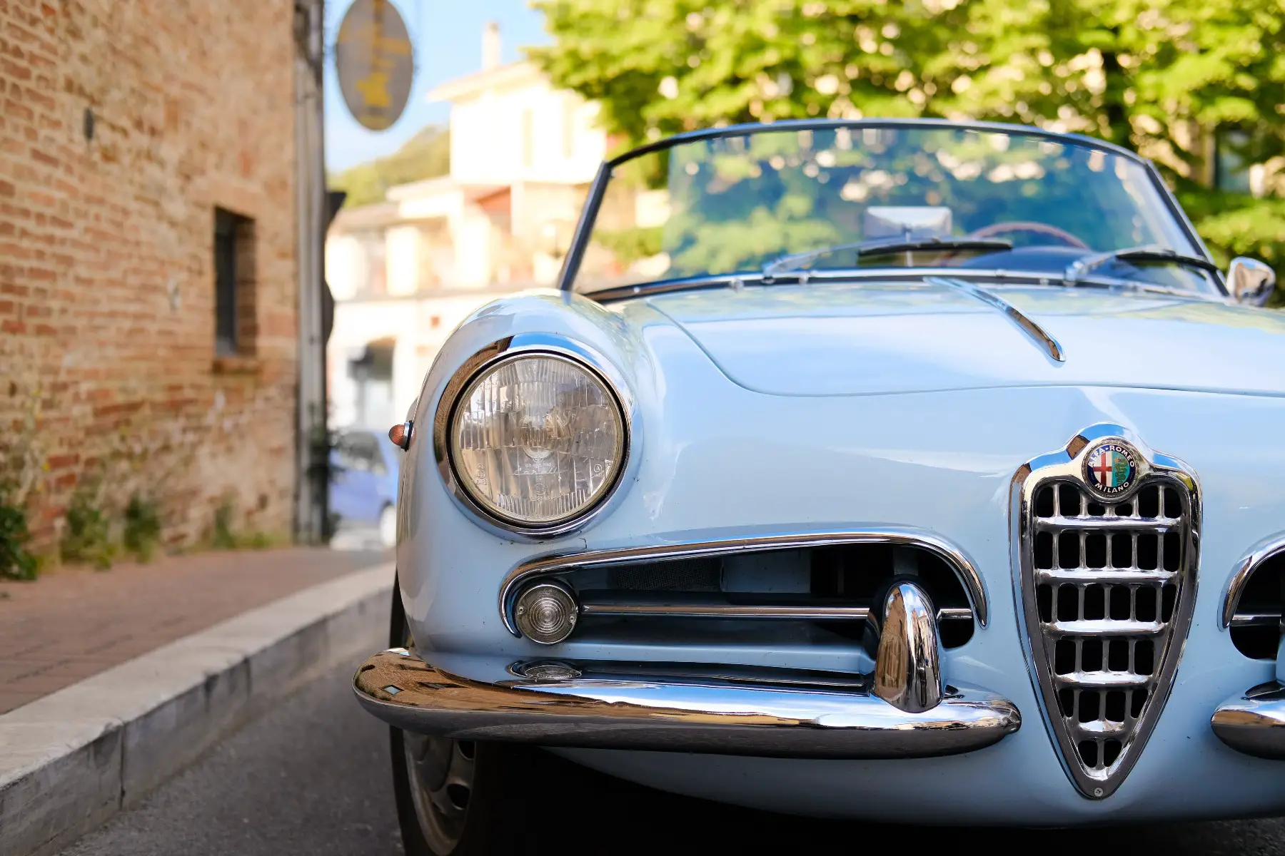A close up shot of a blue Alfa Romeo parked in a street in Italy