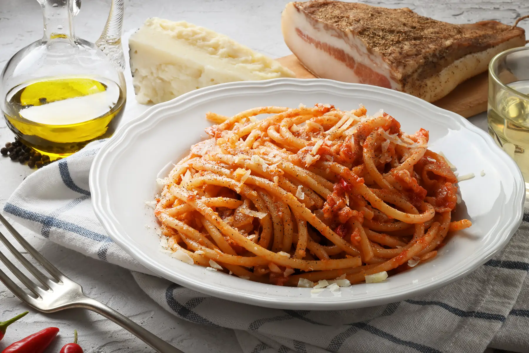Amatriciana. Spaghetti in reddish sauce on a circular white plate