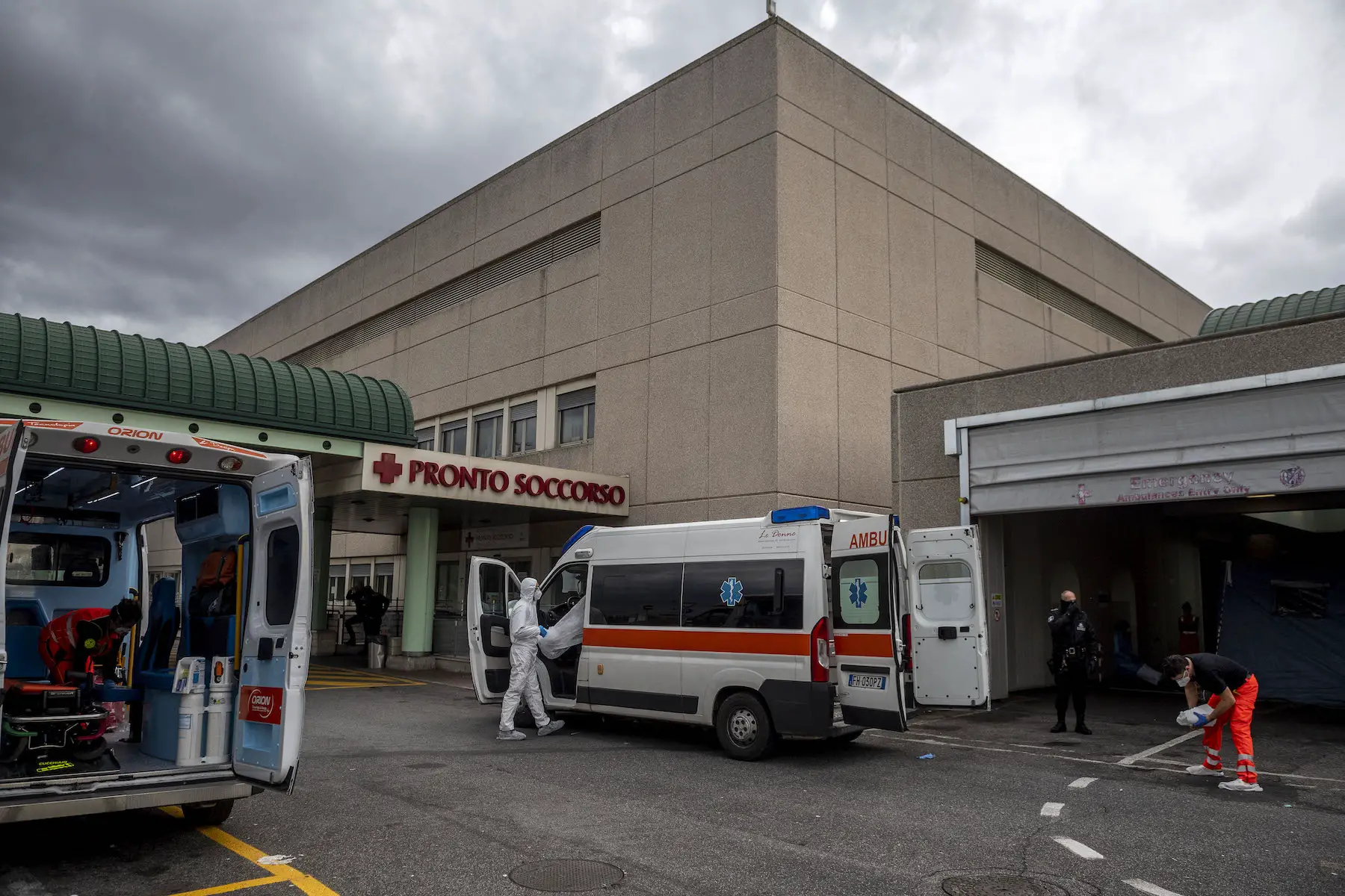 Ambulances are parked outside a Rome hospital; a sign reads emergency room in Italian