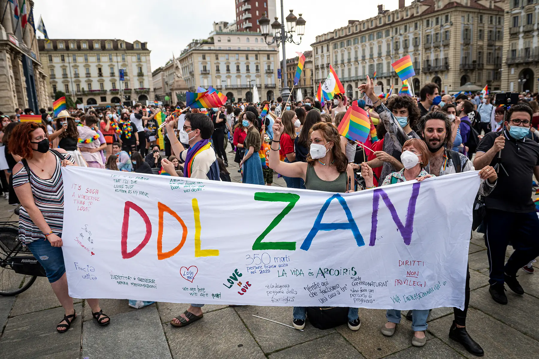 Protesters waving rainbow flags and holding a banner with 'DDL ZAN' written on it