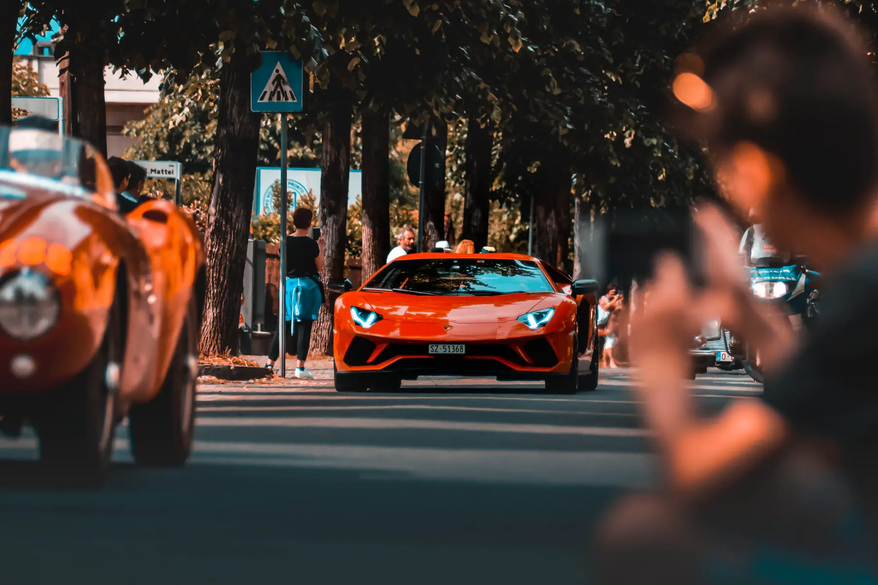 A red Lamborghini driving along a quiet street in Milan, Italy