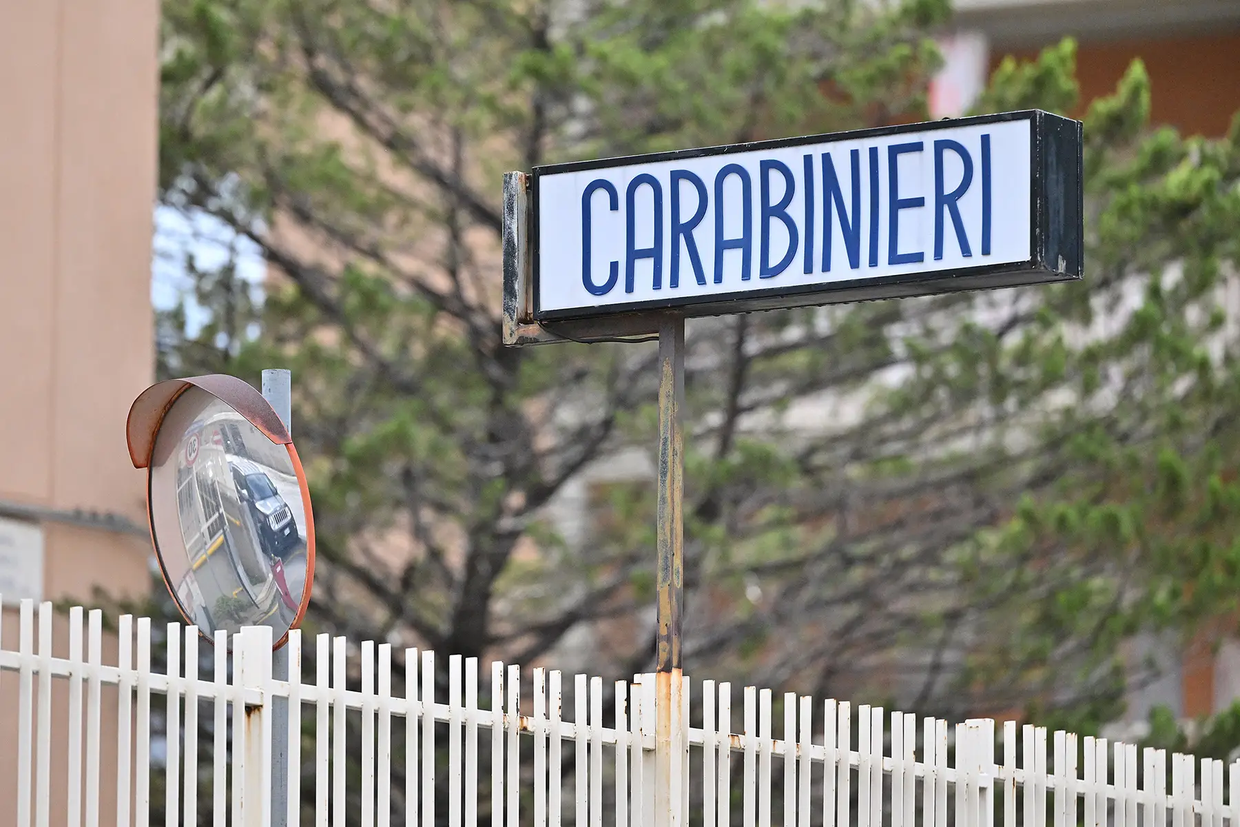 Outside a police station, a sign says 'Carabinieri'