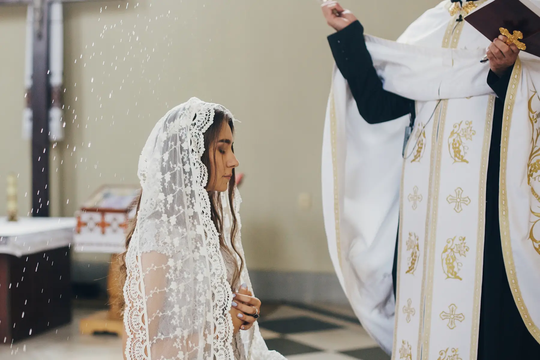 A Catholic priest performs a blessing on a bride with holy water