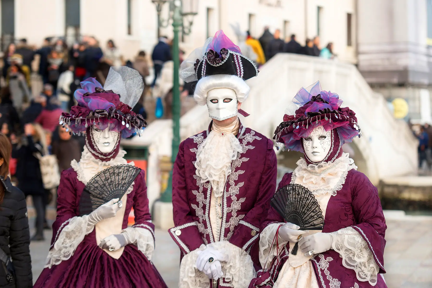 People wearing costumes of white masks and old-fashioned purple clothes