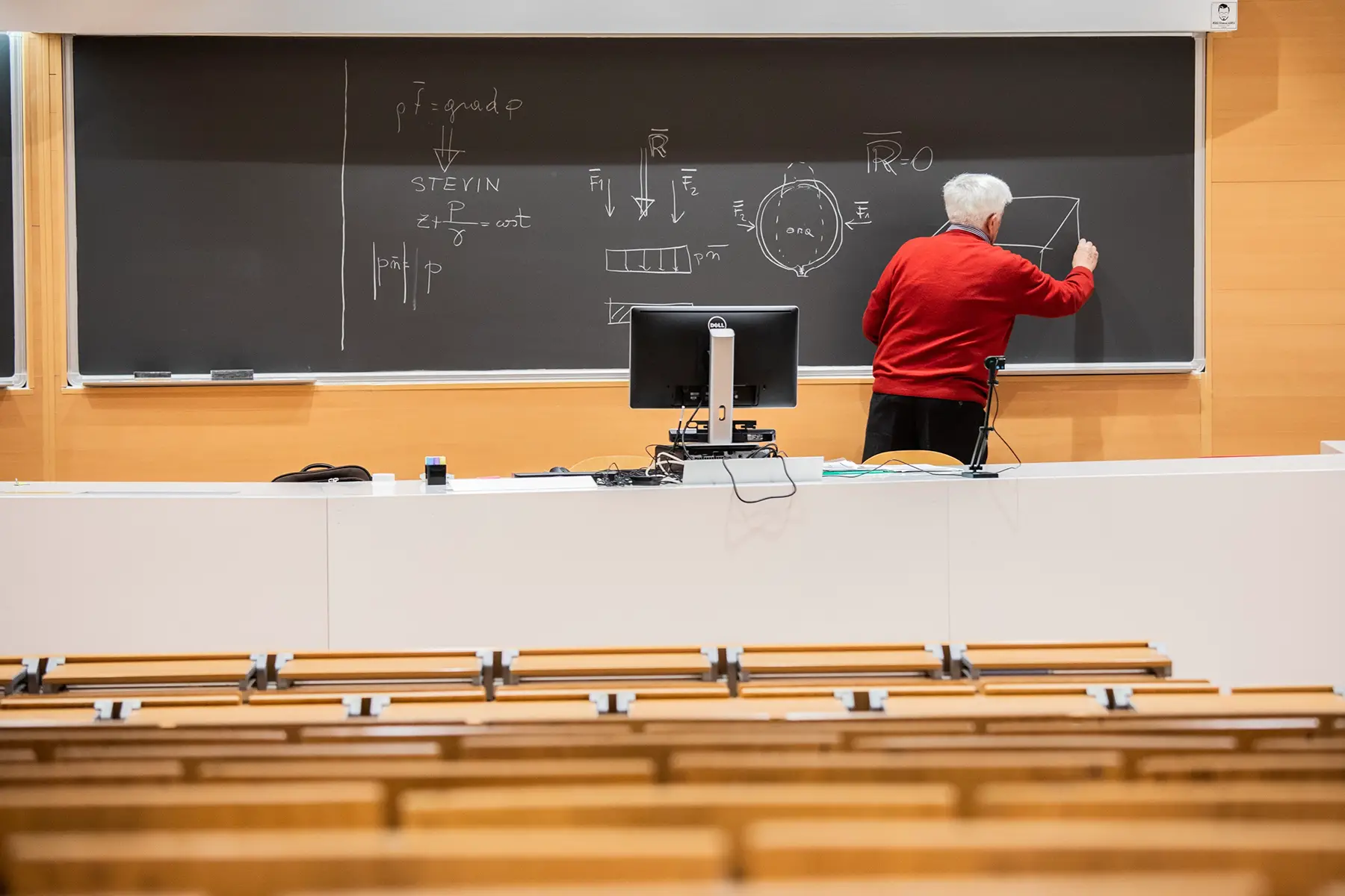 Professor at Politecnico di Milano delivers an engineering lecture online, empty classroom