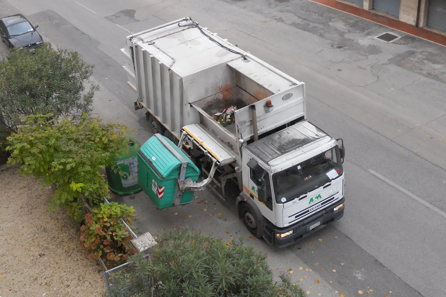Garbage truck lifting up a garbage container.