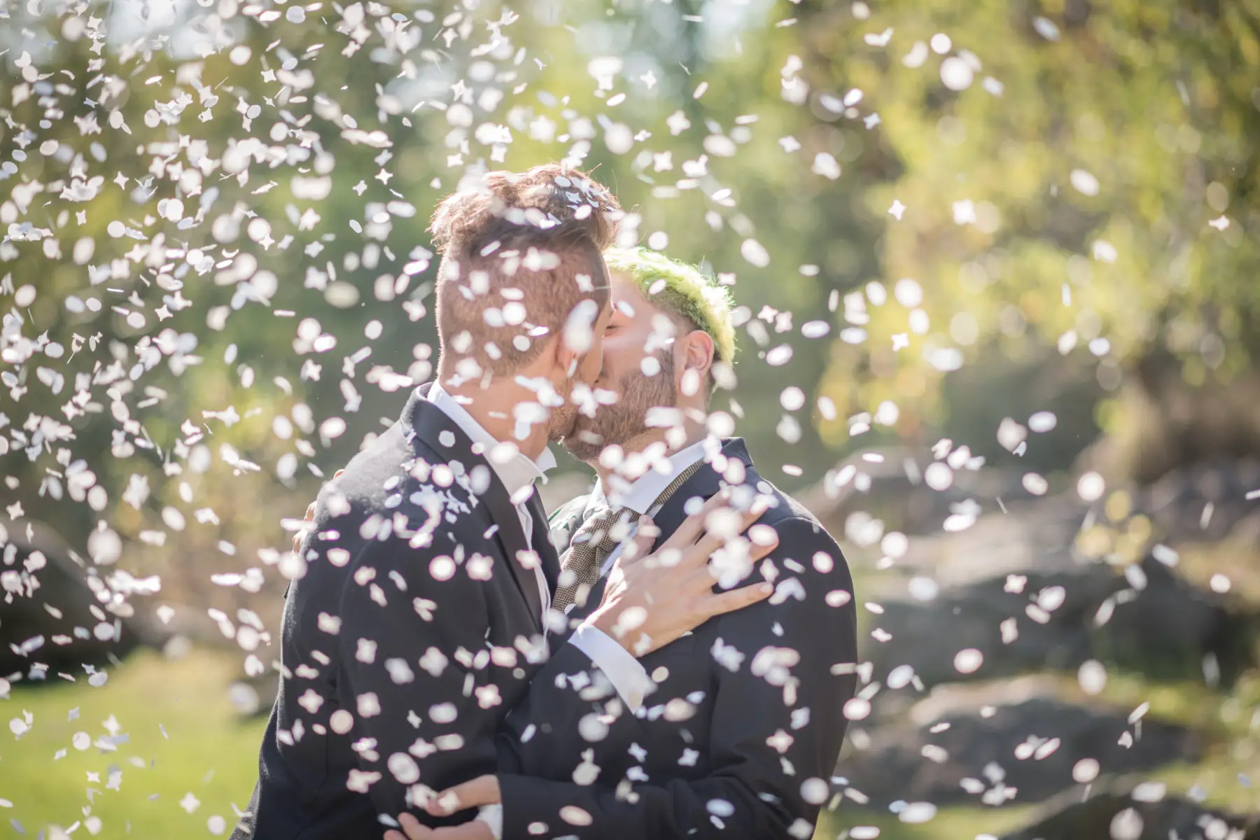 A gay bridal couple kissing, confetti flying around them