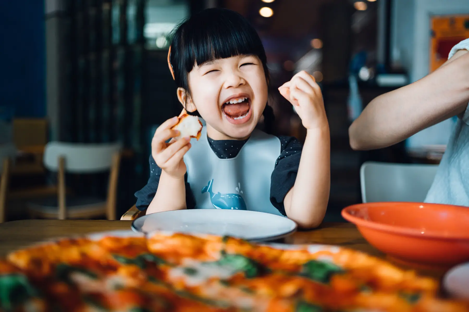 Girl laughing and eating pizza at restaurant