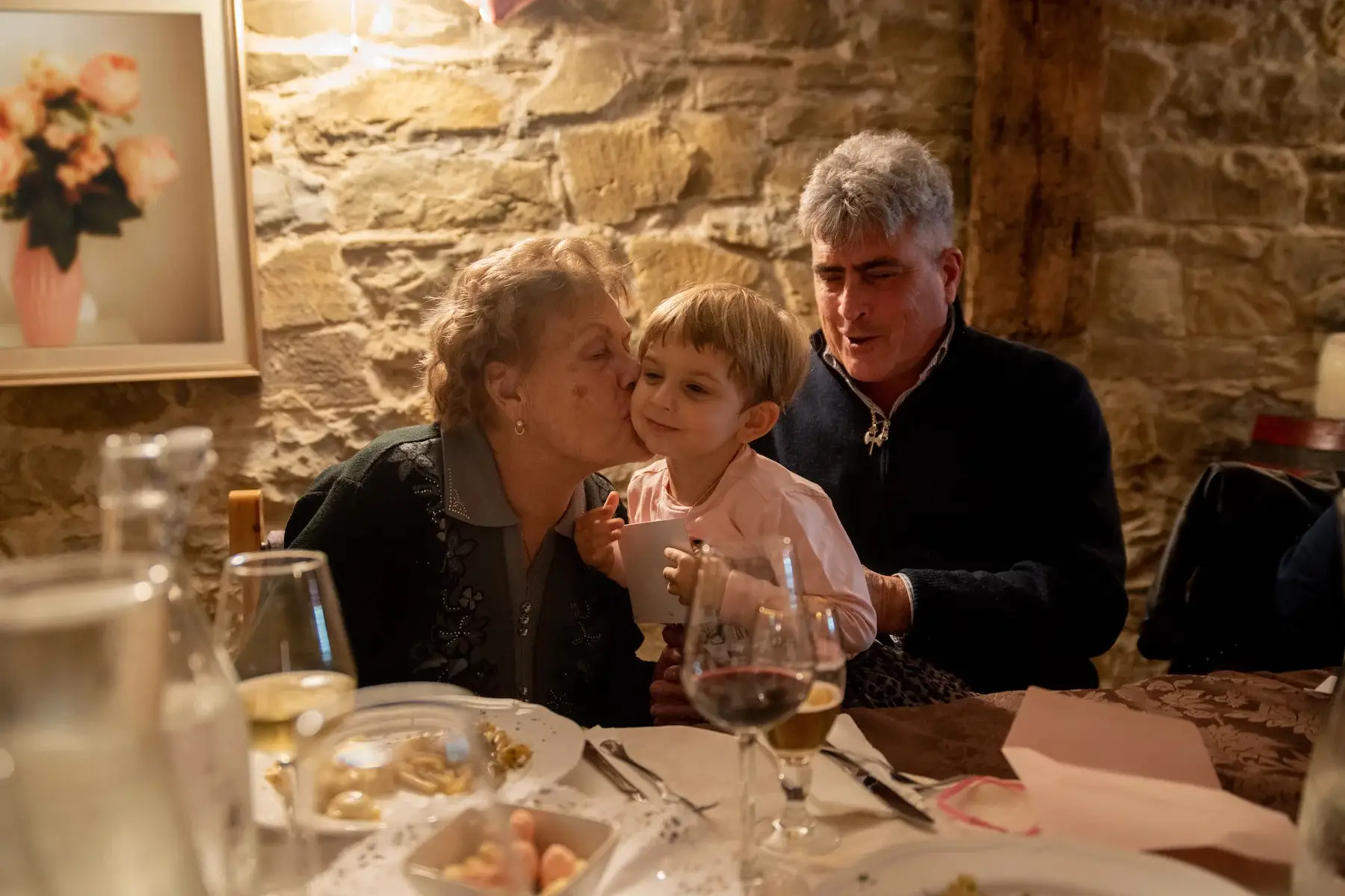 Grandparents hold their young grandchild while dining at a restaurant