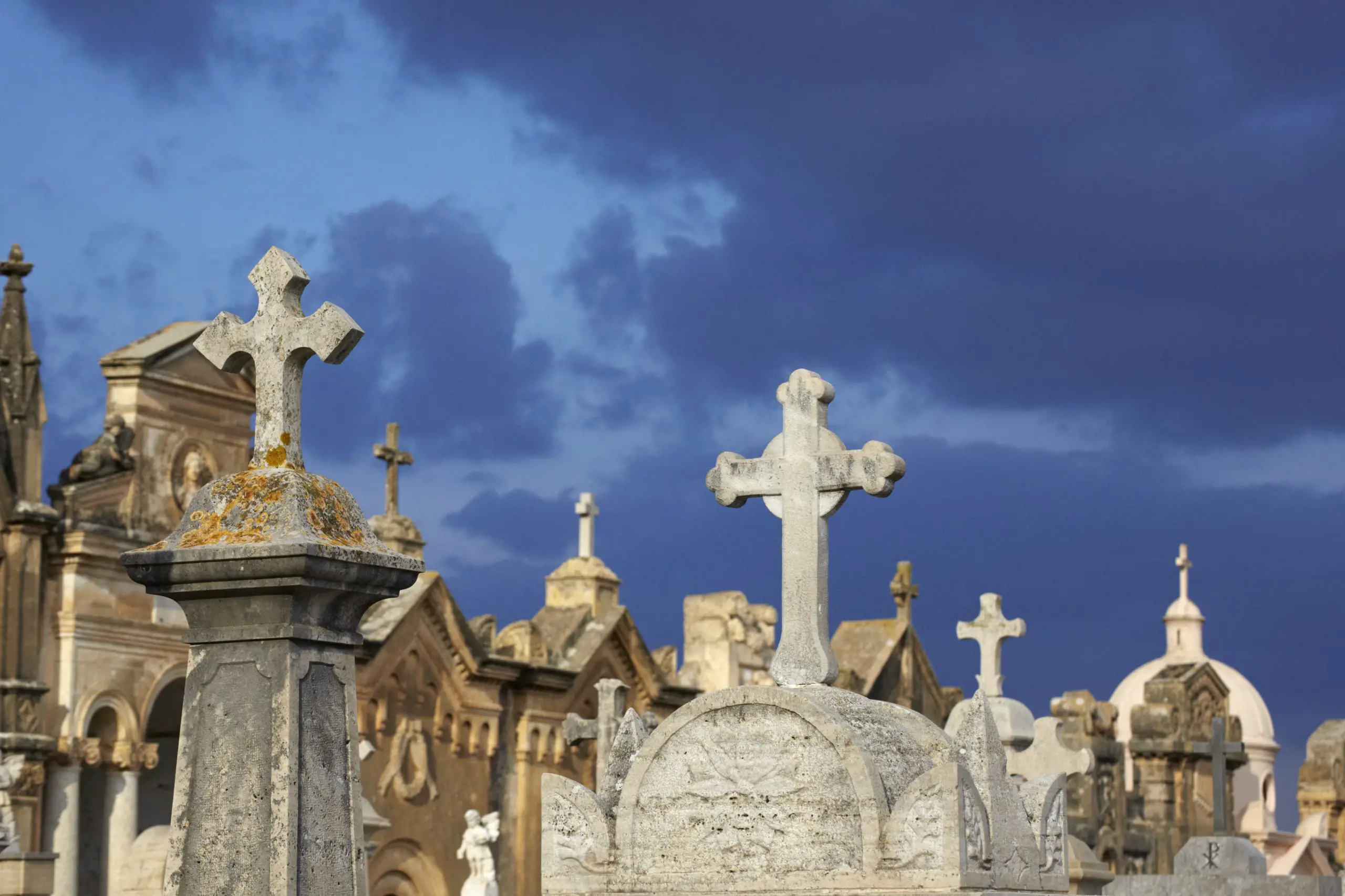 Italy, Sicily, Alcamo, gravestones against moody sky