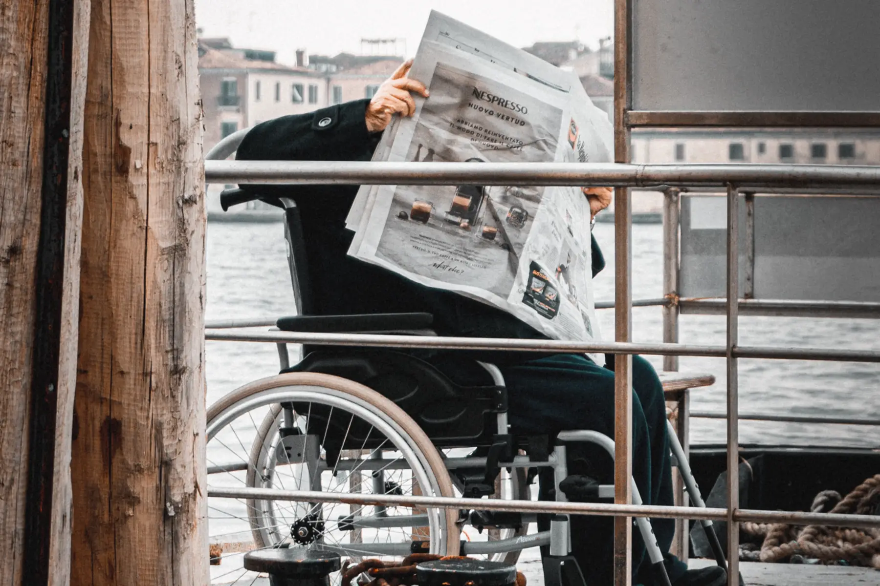 A person sitting in a wheelchair reading a newspaper