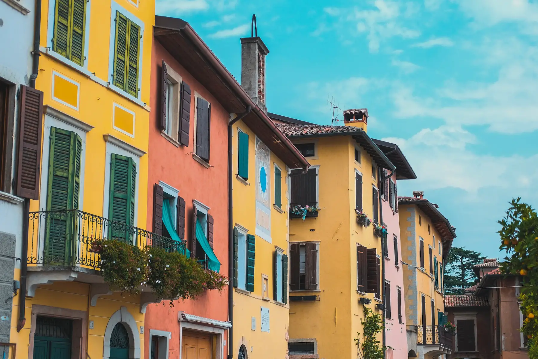 A row of colorful, traditional Italian houses with a bright blue sky above
