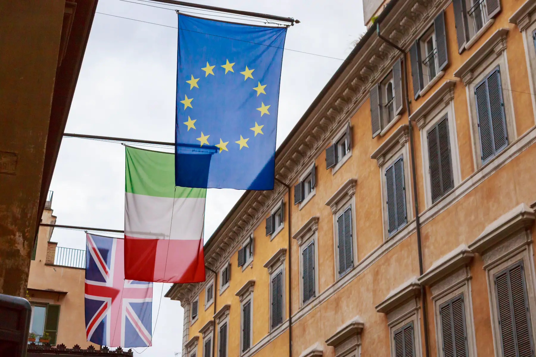 Flags of the UK, Italy, and Europe hanging outside a building in Rome, Italy.