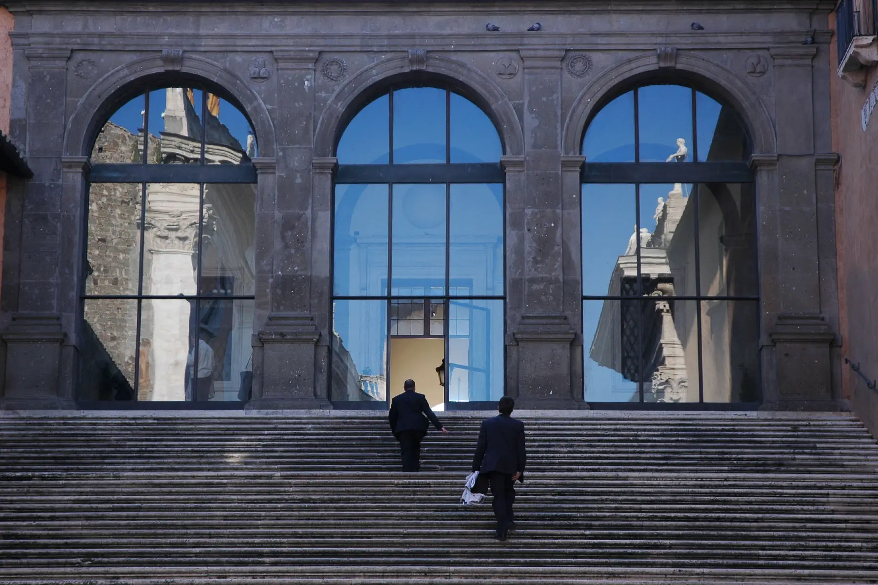 Two business men running to going up the stairs of a court building in Rome.