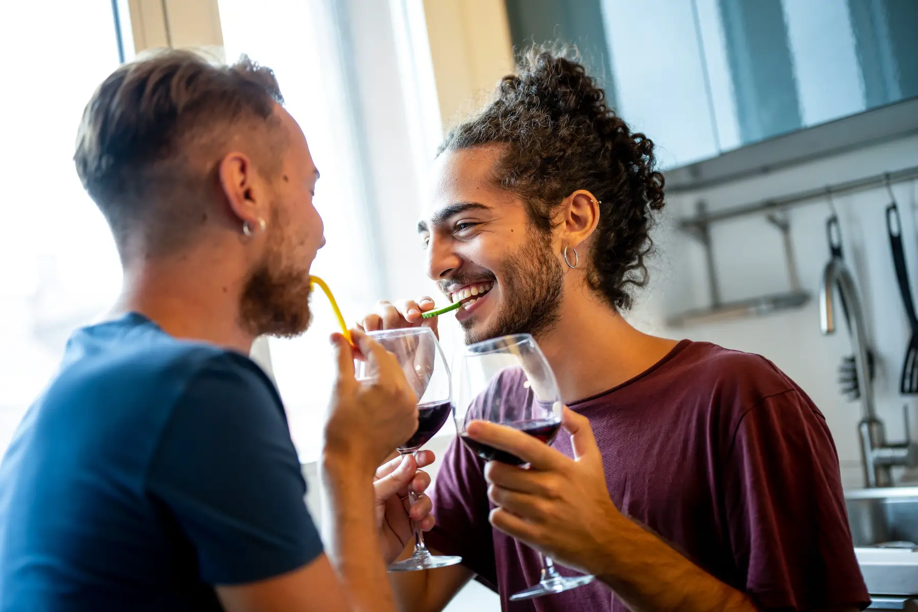 A same-sex couple flirting while drinking red wine