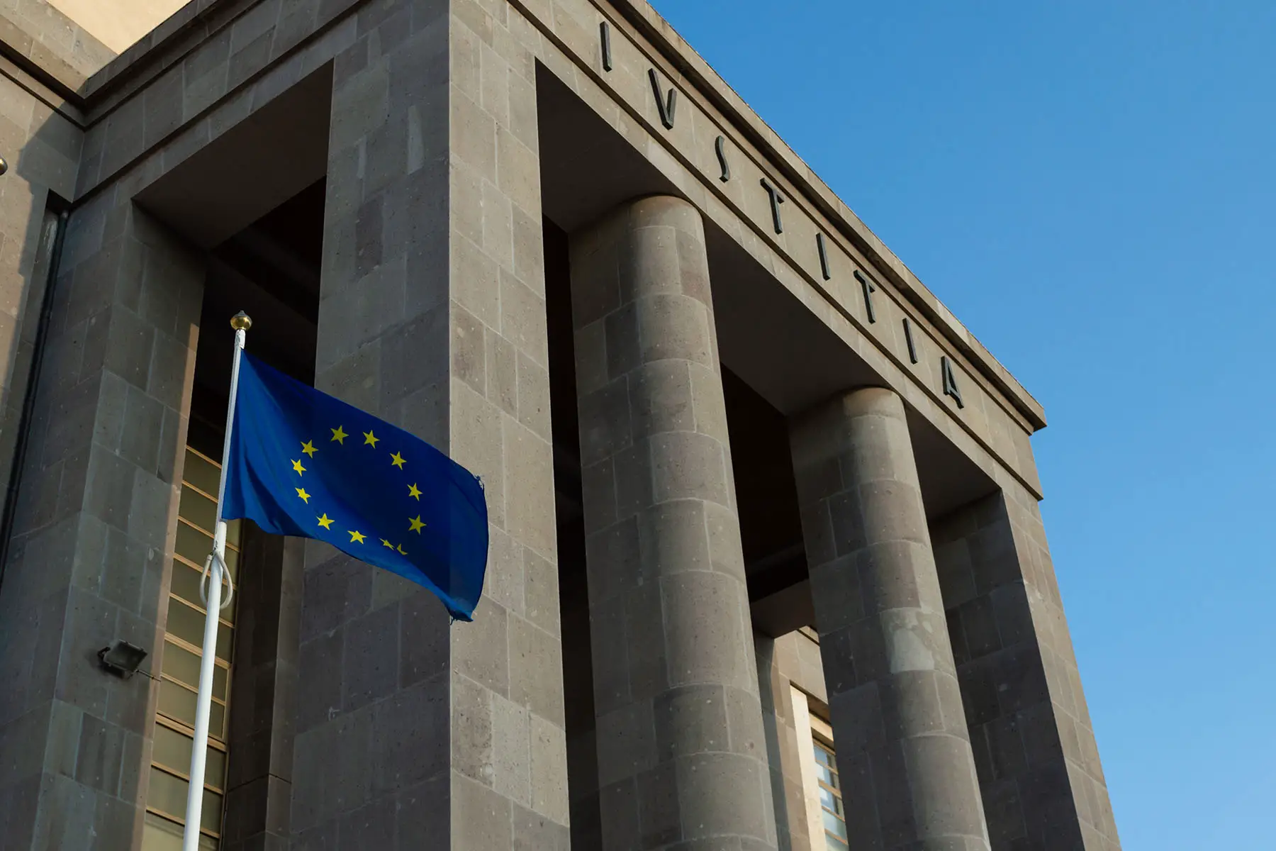 The European flag waving outside a tribunal with the latin word IUSTITIA ( Justice), in Cagliari, Italy.
