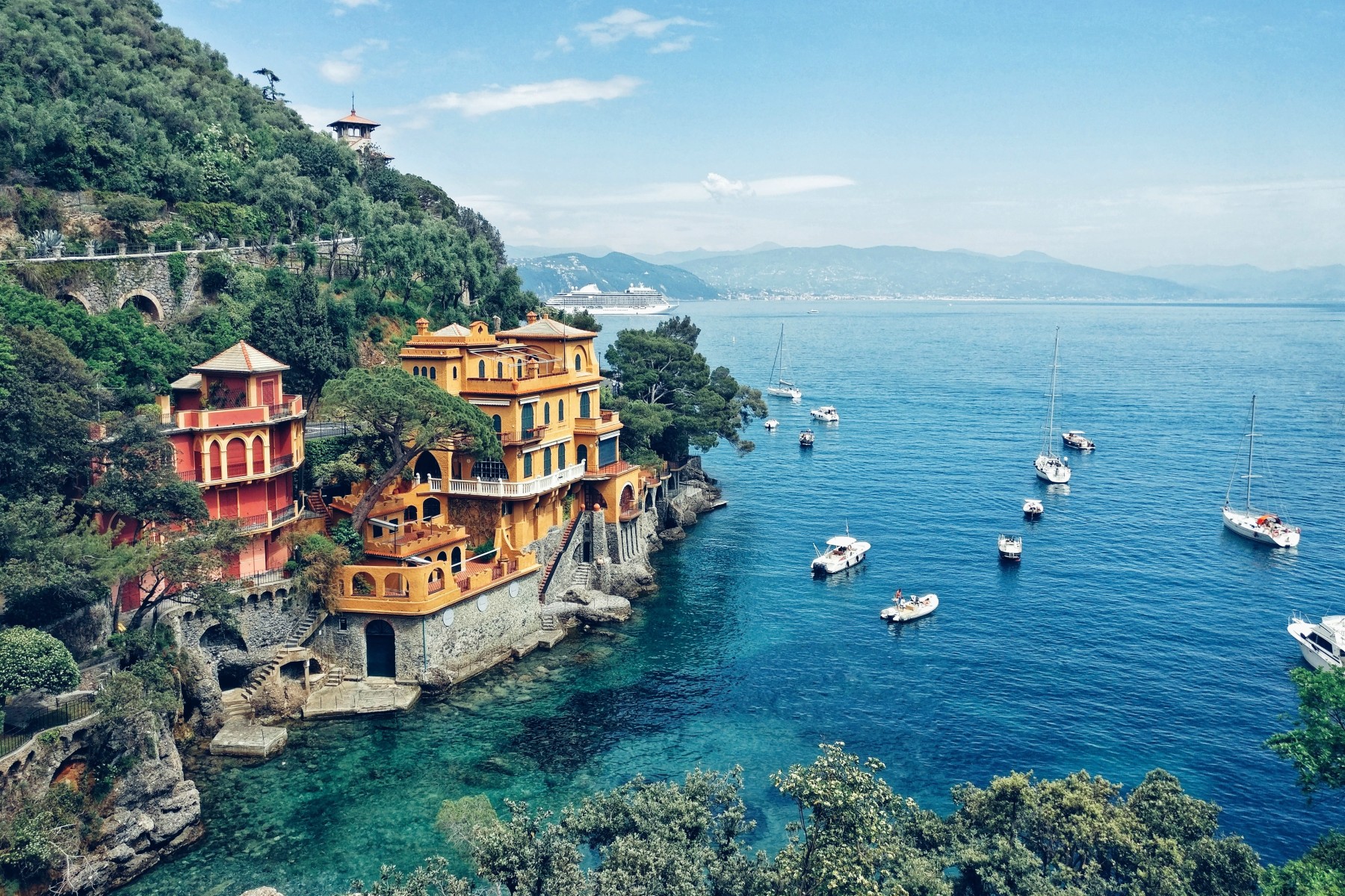 View of houses on a hill top near the water front, surrounded by trees in Portofino, Italy.
