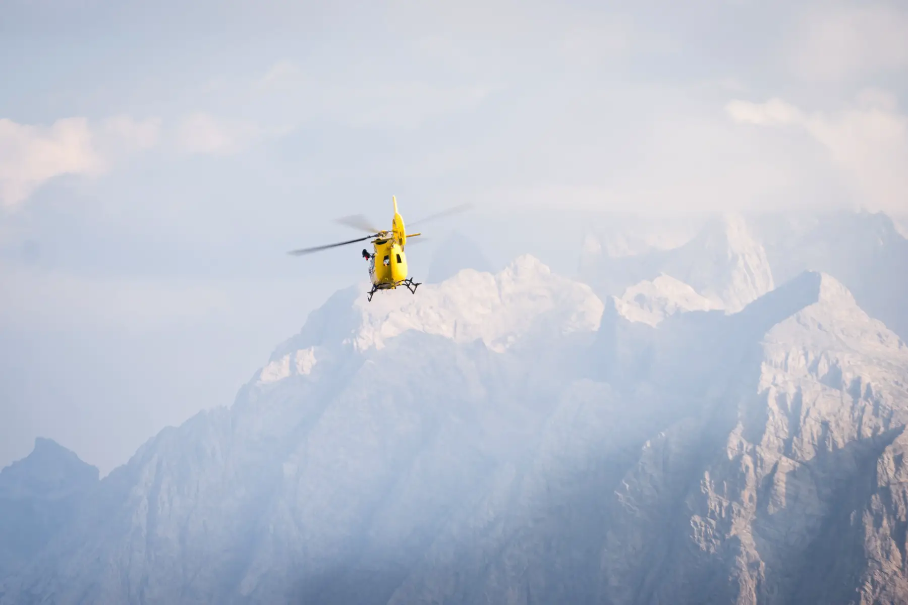 Medical helicopter flying through the air near the Italian Dolomites.