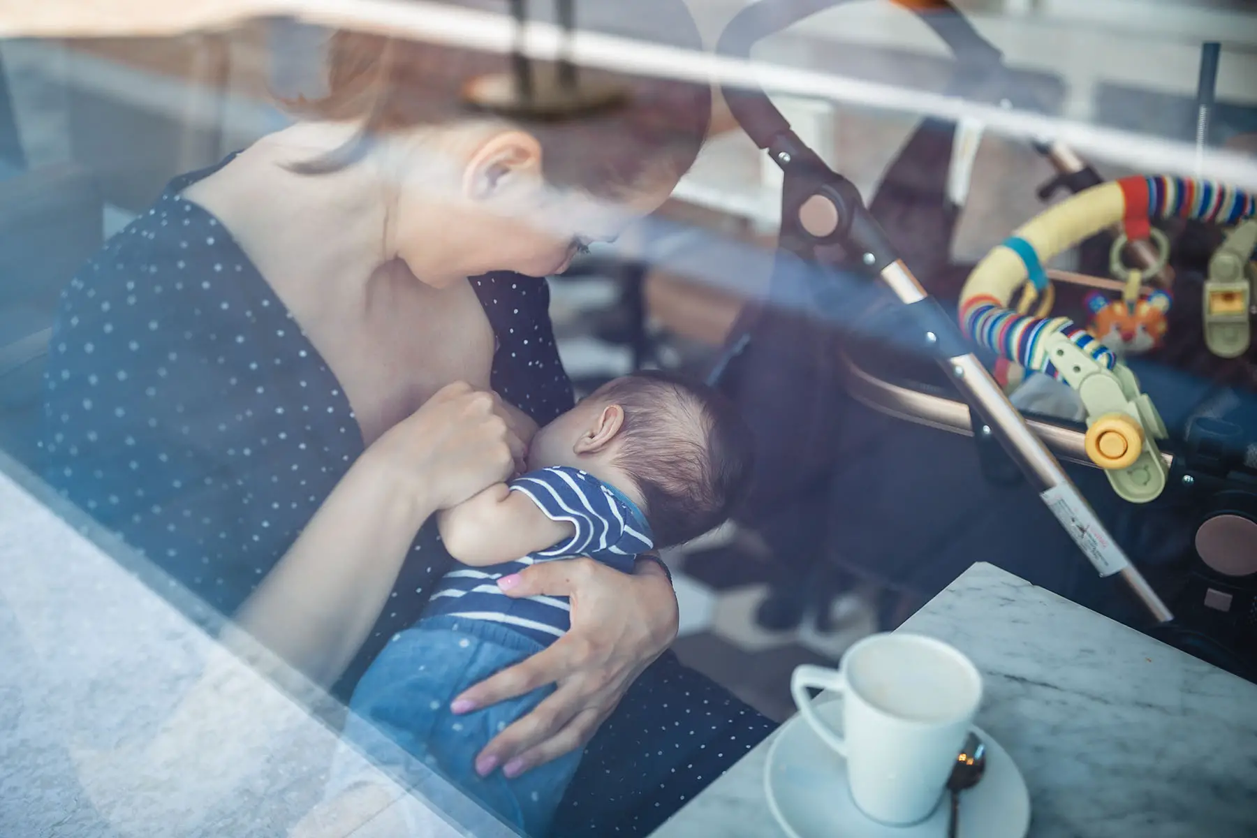 Mother breastfeeding her baby in a restaurant. Photo taken from outside.