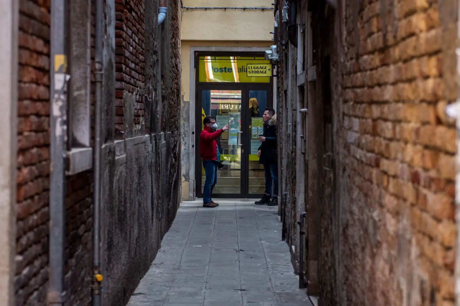 Two people standing outside a post office in Venice, Italy.