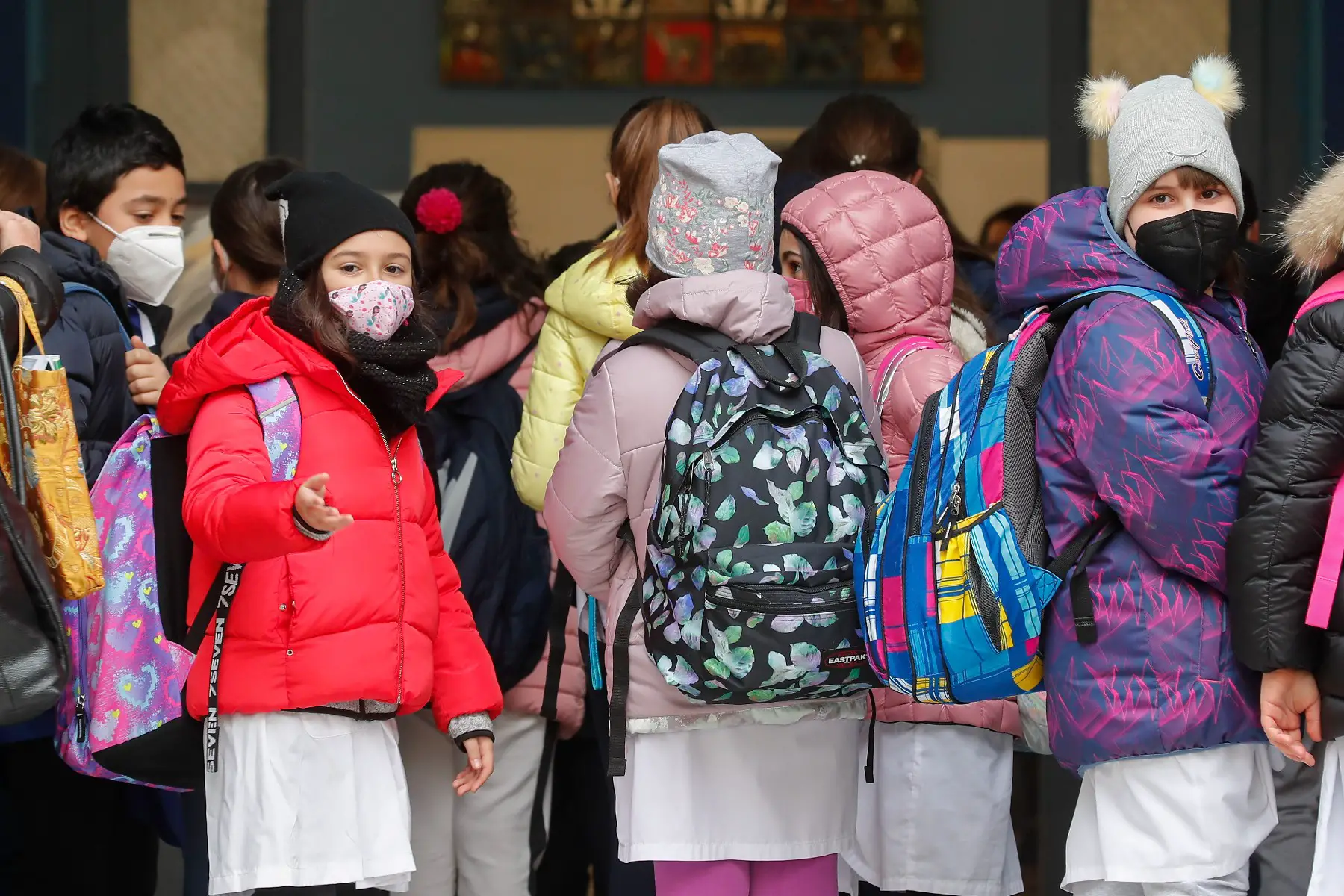 Pupils wearing protective masks enter  an elementary school. 