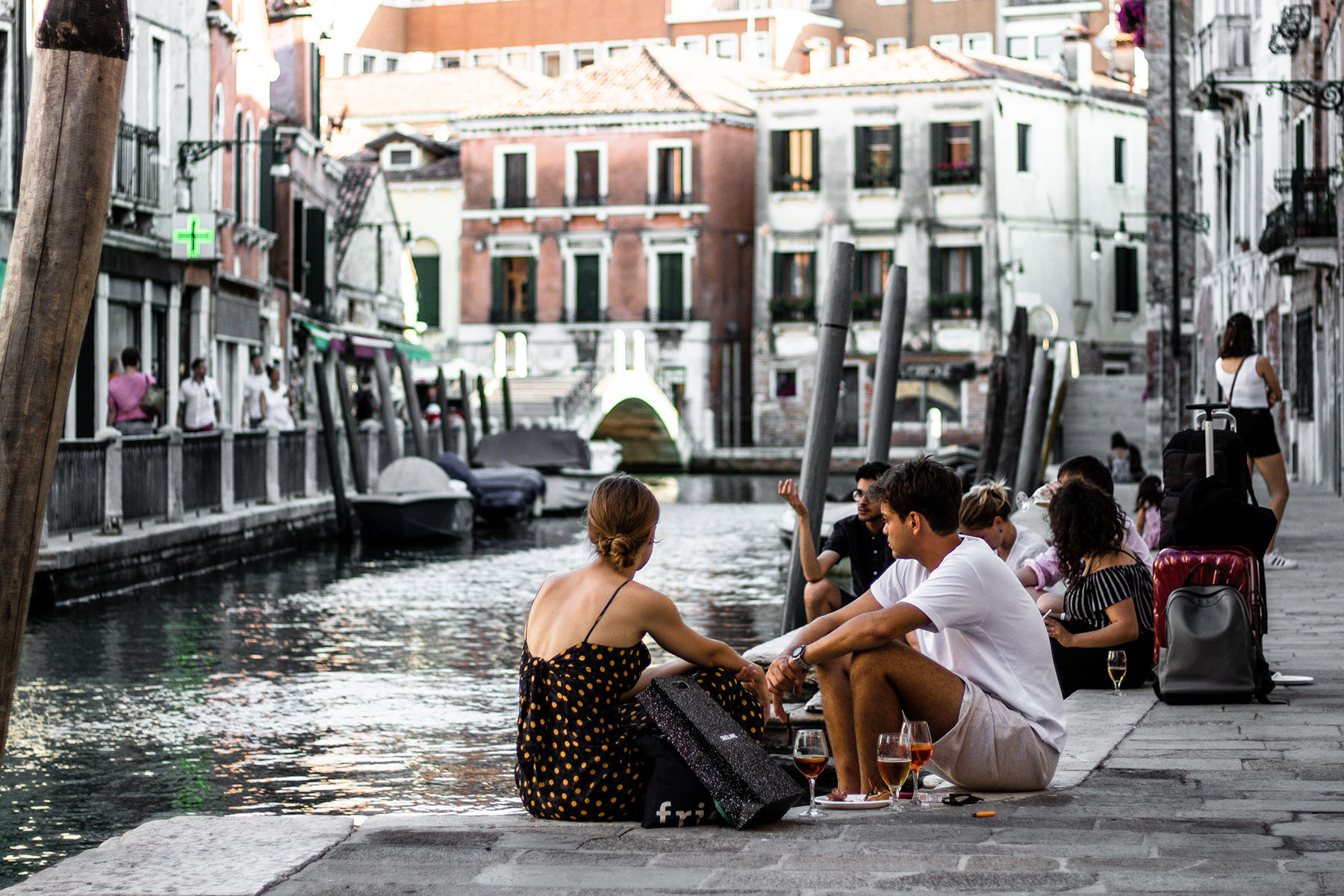 People having drinks on the side of the canal in Venice, Italy.