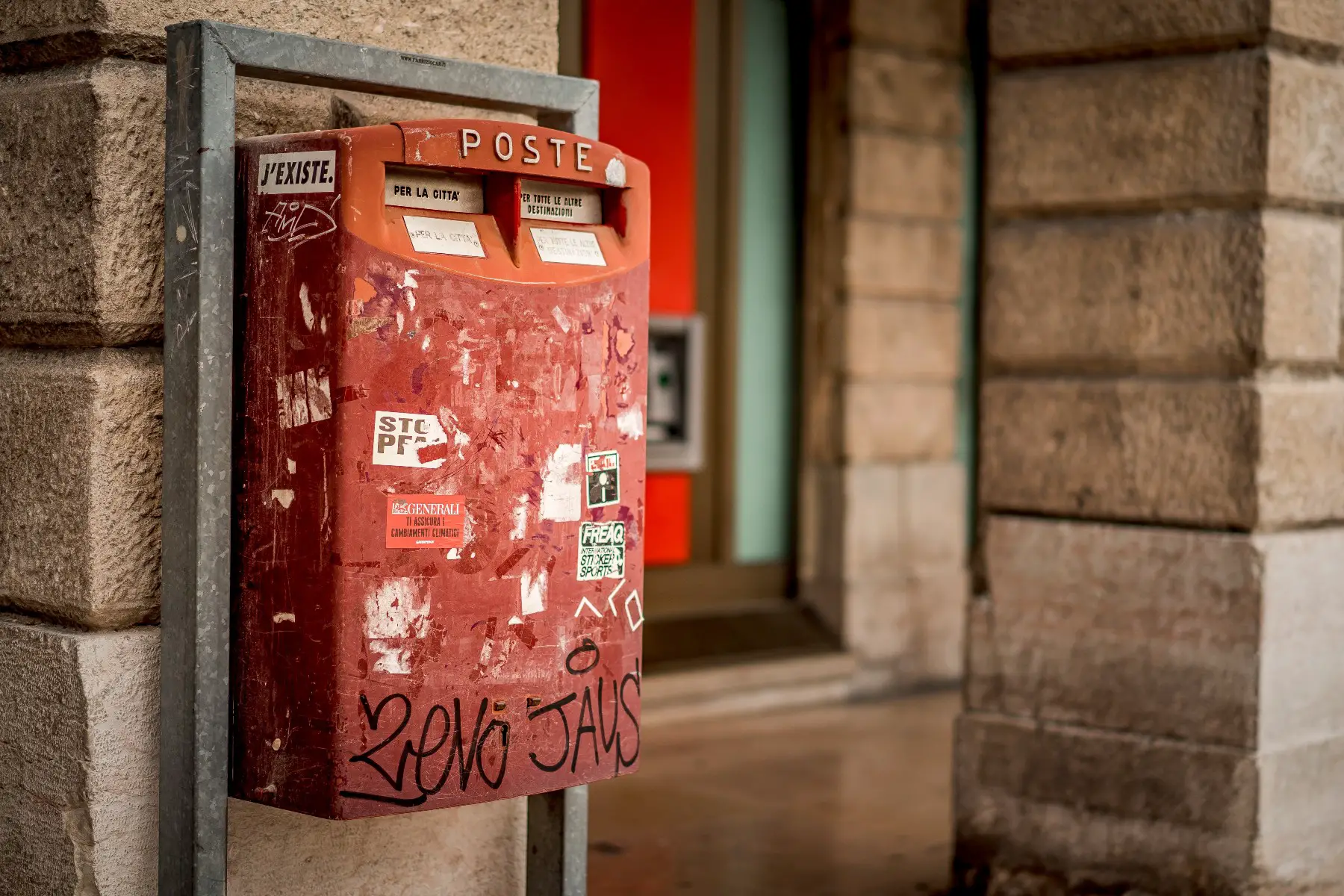 A close-up shot of a red mail box mounted on a brick wall in Verona, Italy
