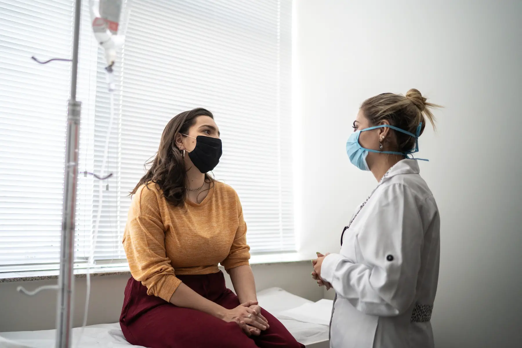 Patient talking to doctor at a women's healthcare center; both are wearing masks