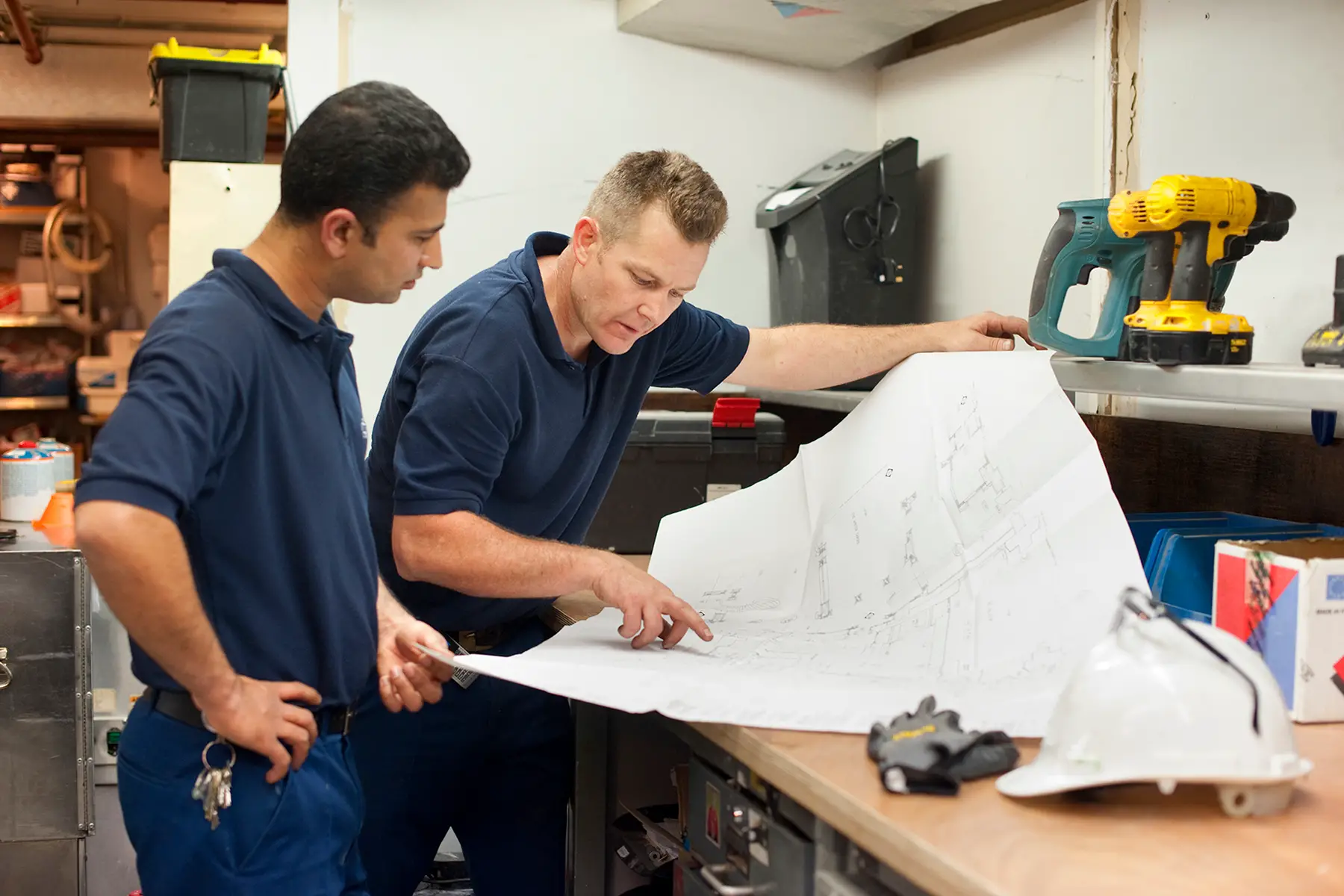 Men in a workshop look at plans on a big piece of paper