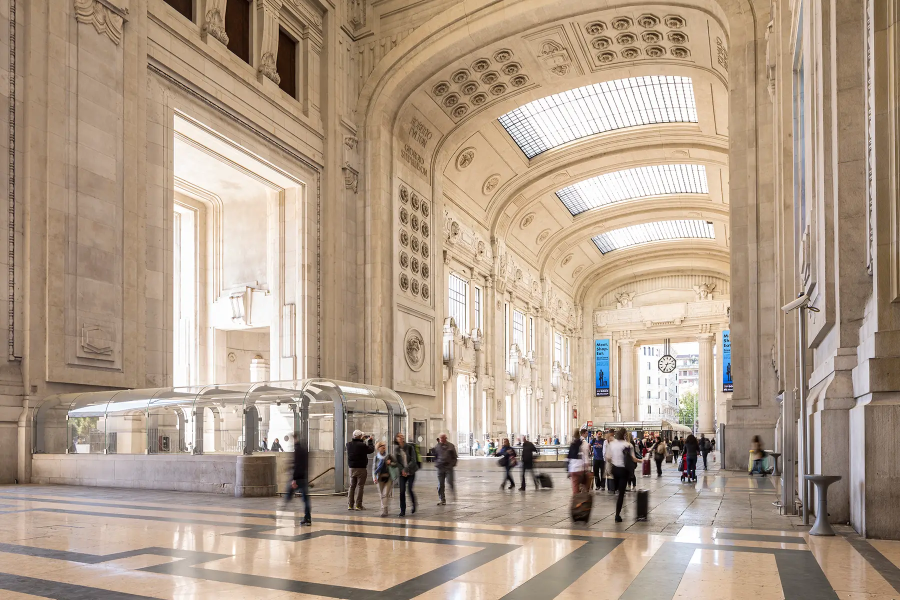 Interior of a grand railway station with marble arches and commuters - 	Milano Centrale railway station in Milan