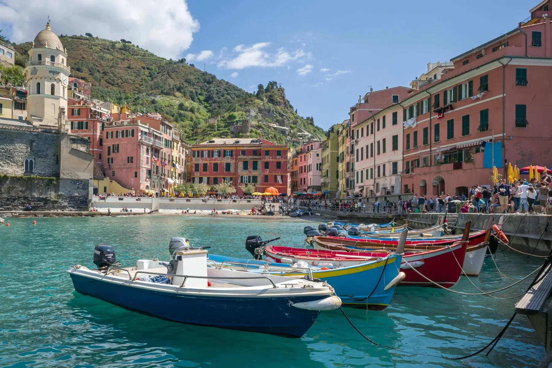Colorful fishing boats moored in the crystal clear Mediterranean water at the historical town of Vernazza, Italy