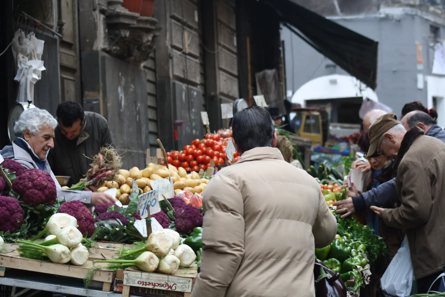 Customers buying their vegetables from an outdoor market in Catania