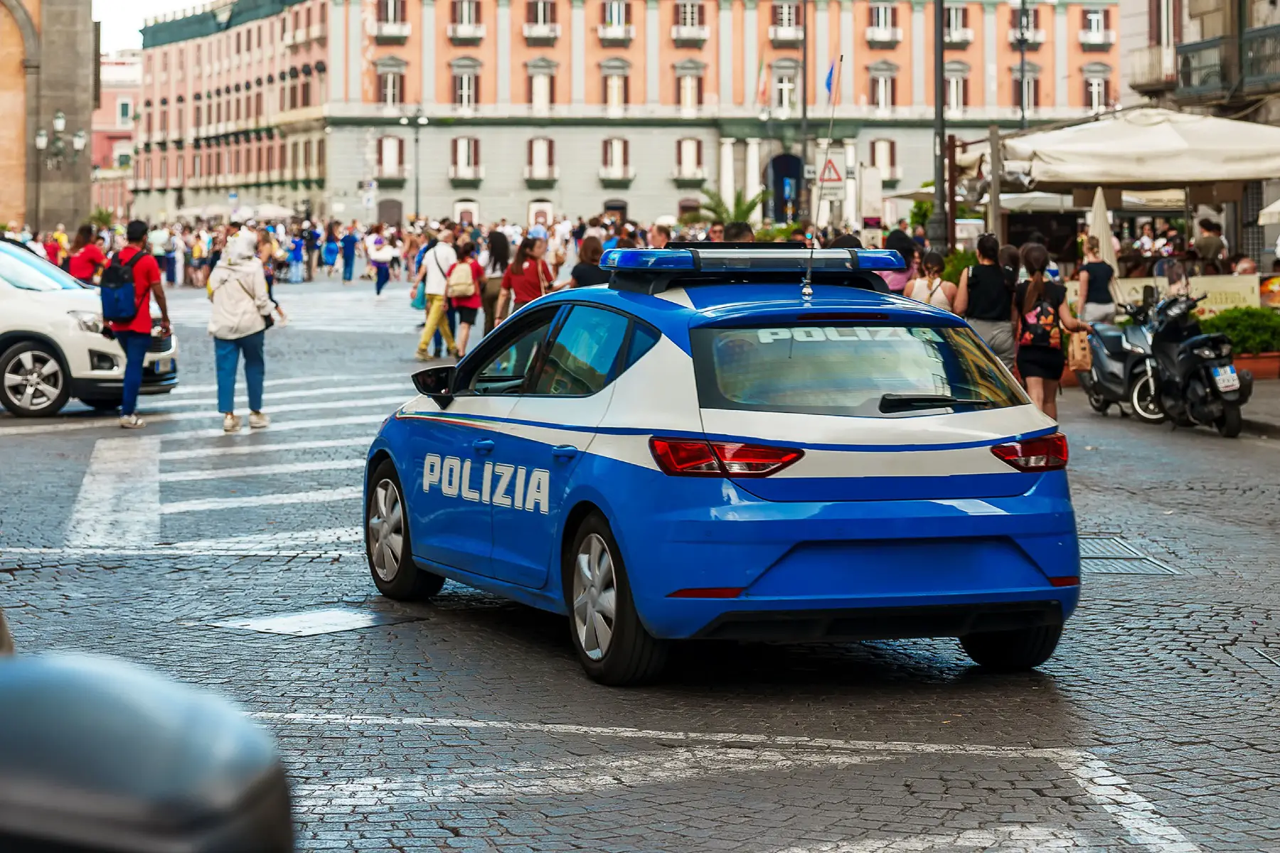A blue and white police car patrolling the old city in Naples