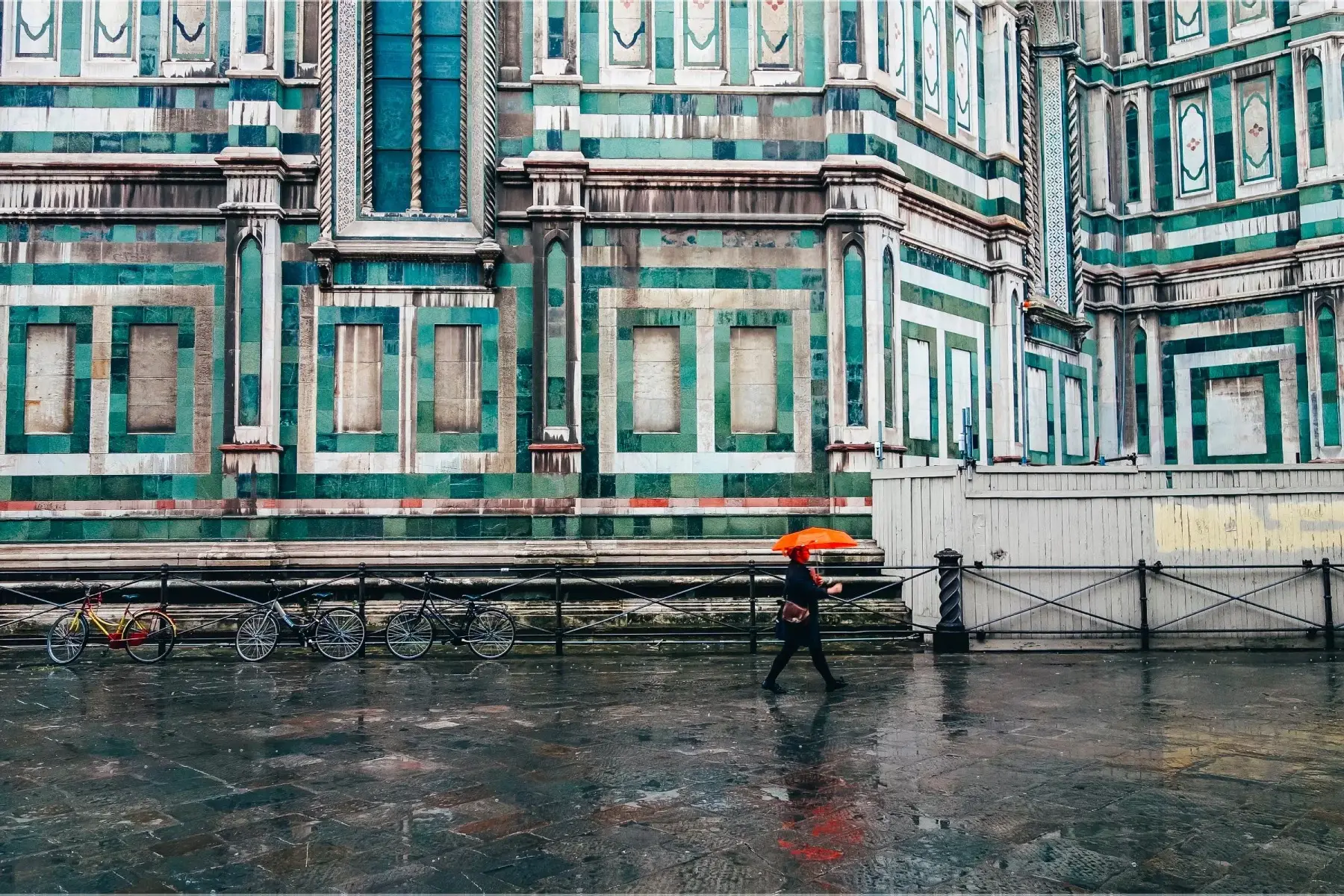 Person walking to work with orange umbrella on a rainy day in Florence