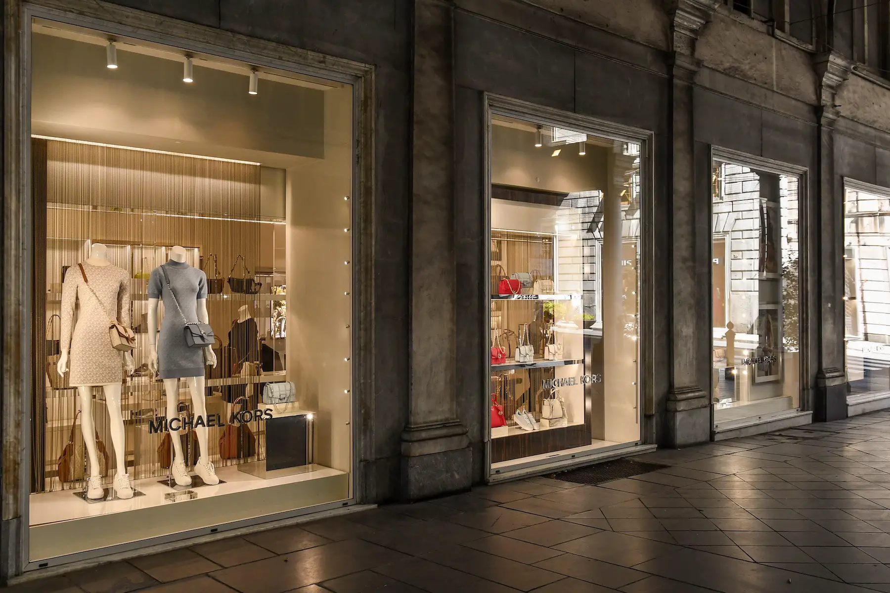 Purses and dresses on display in the windows of a Michael Kors store inside Galleria Giuseppe Mazzini shopping center, Genoa, Italy