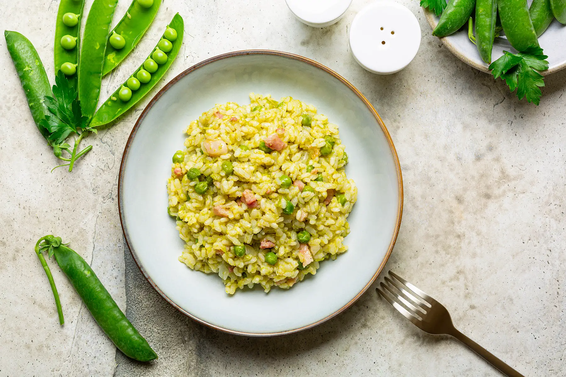 Risi e bisi – a risotto-like dish with peas and ham on a round plate