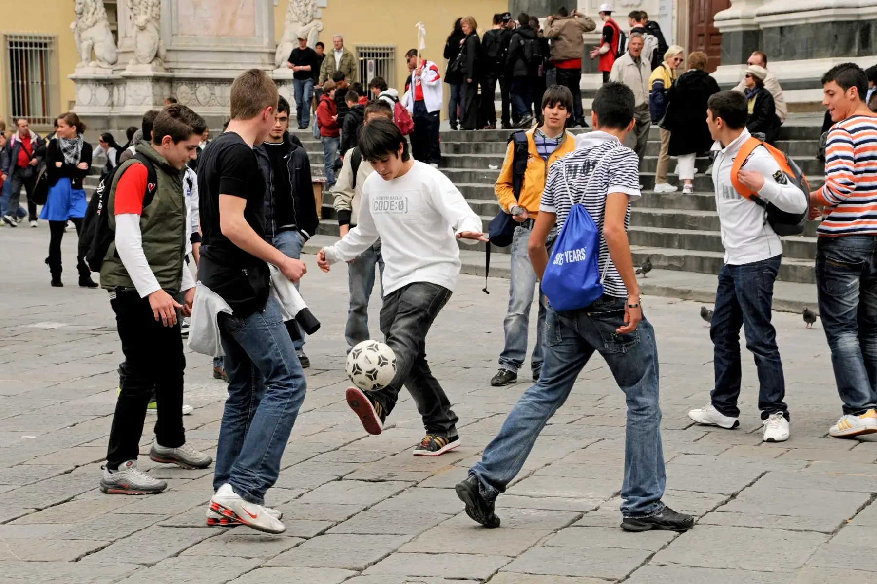 Teenage school boys playing football in a piazza in Florence