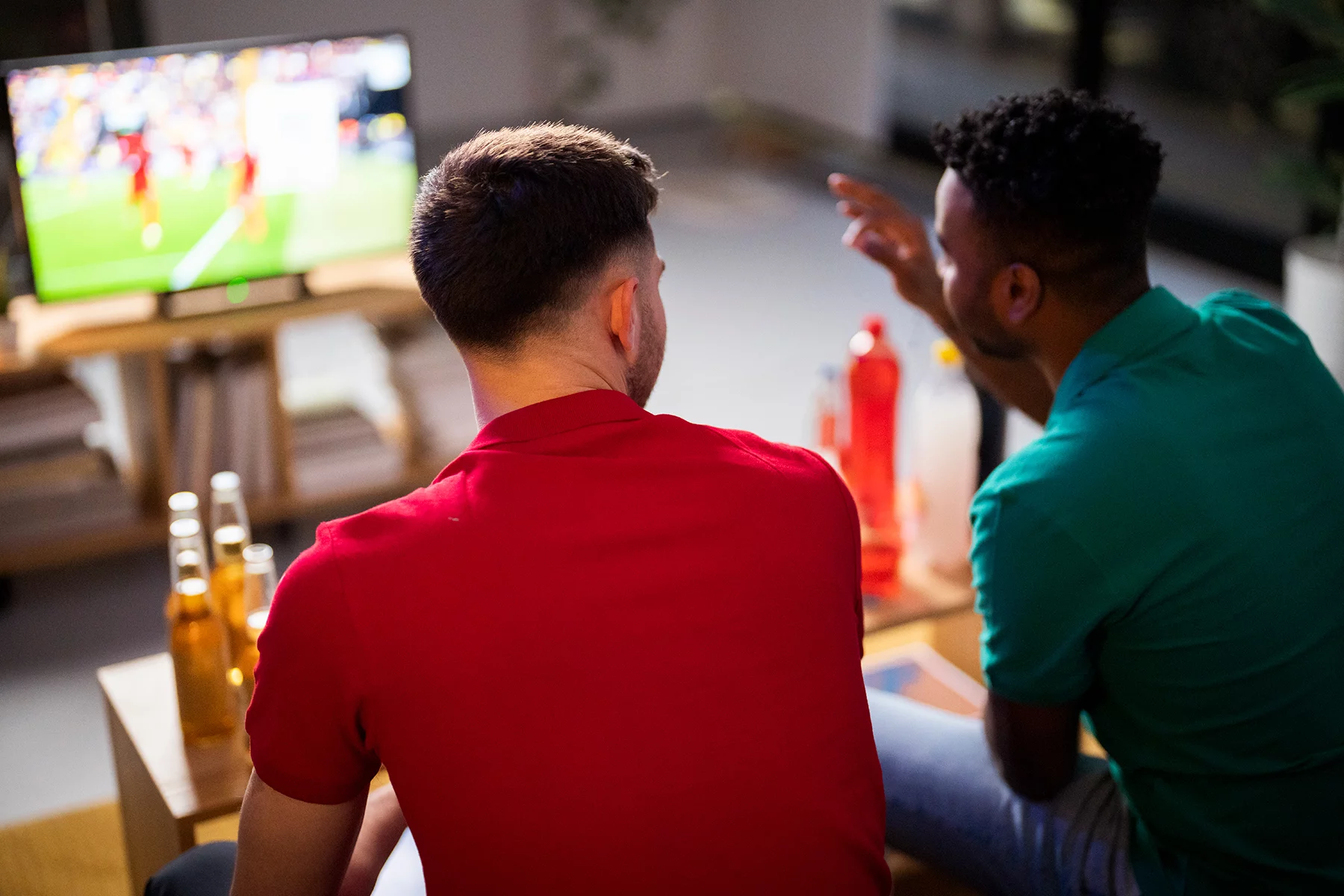Two men watching football on TV and talking