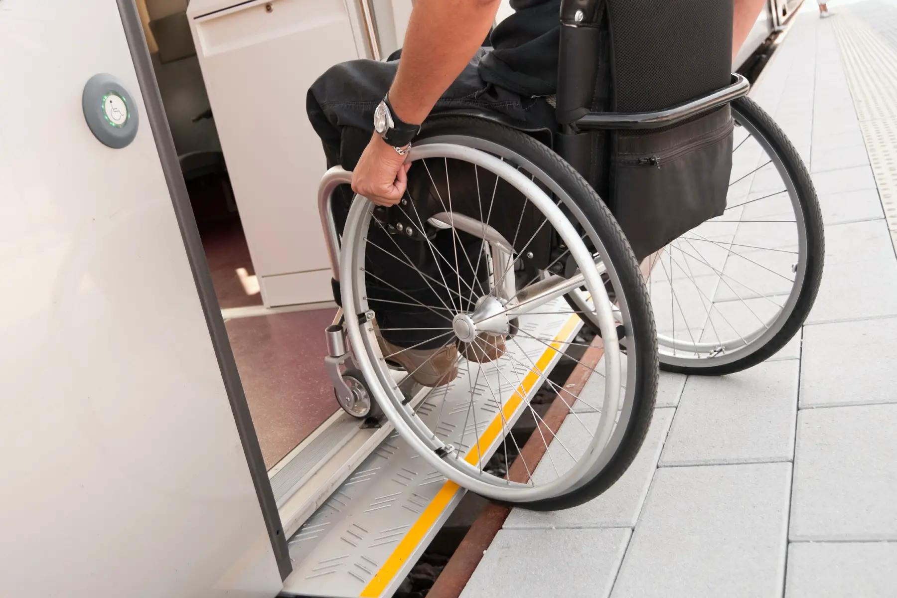 Close up on hand on the wheel of wheelchair as the passenger boards a train