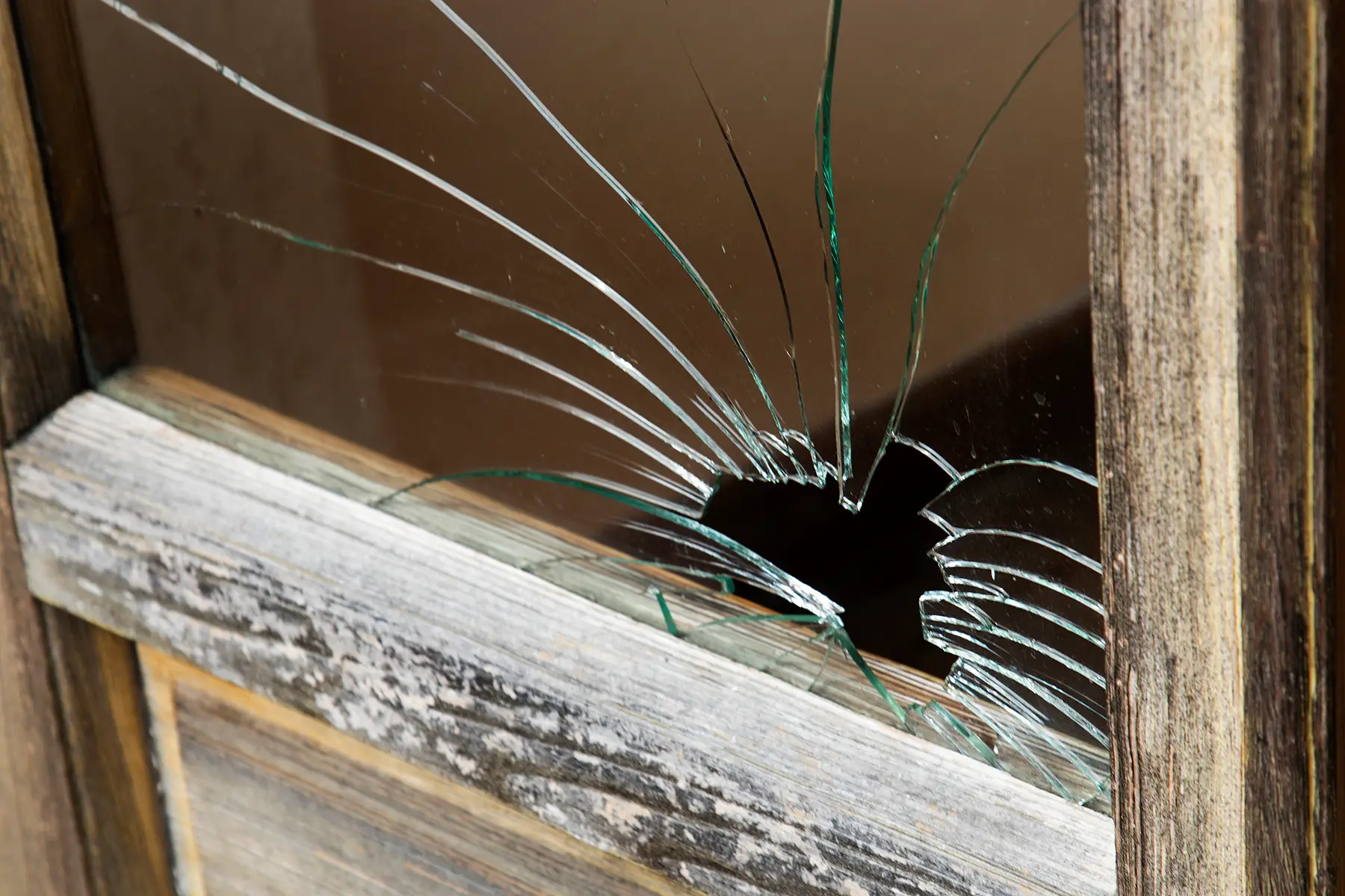 Close-up of a broken window with a worn, wooden pane