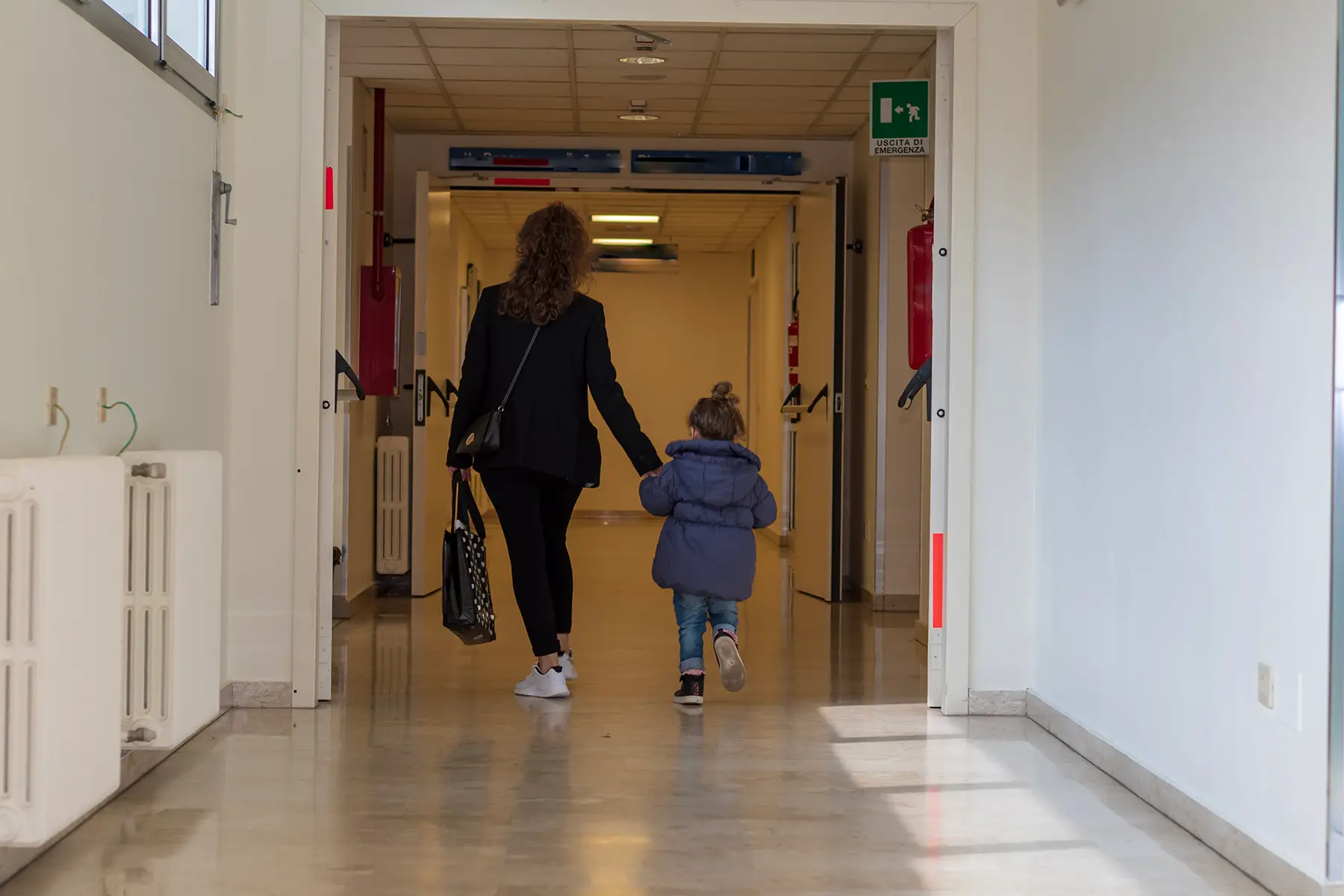 A woman and a child walking down a hospital corridor