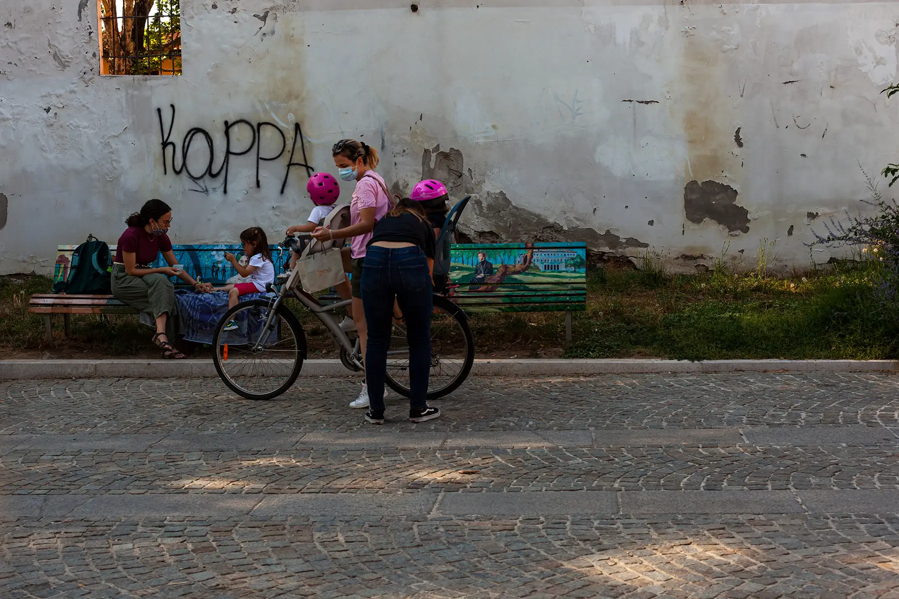 A woman putting two children on a bicycle