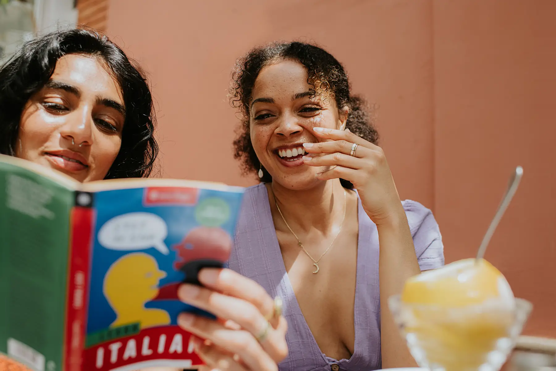 Two friends look at a a book for learning Italian