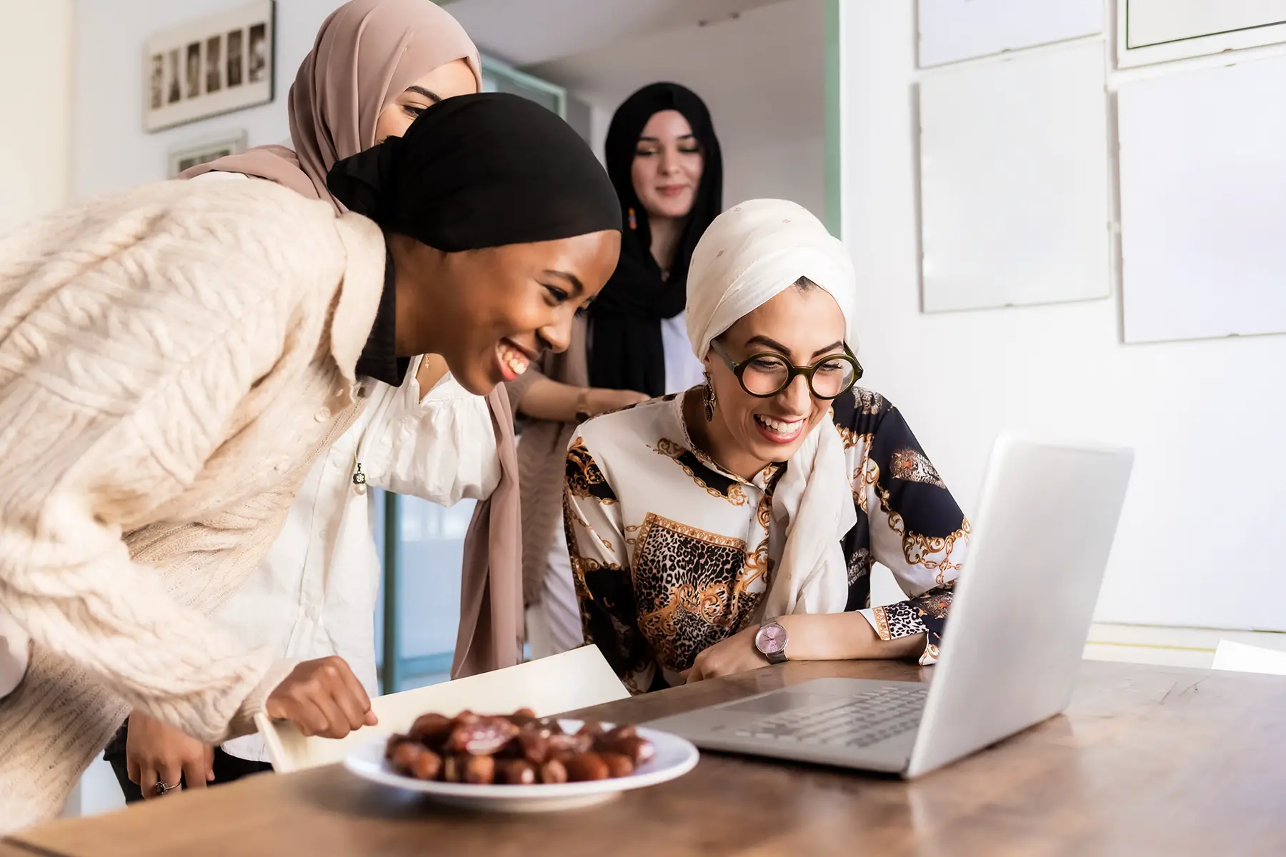 Young muslim women smiling during a video call with a plate of dates placed on the table next to them