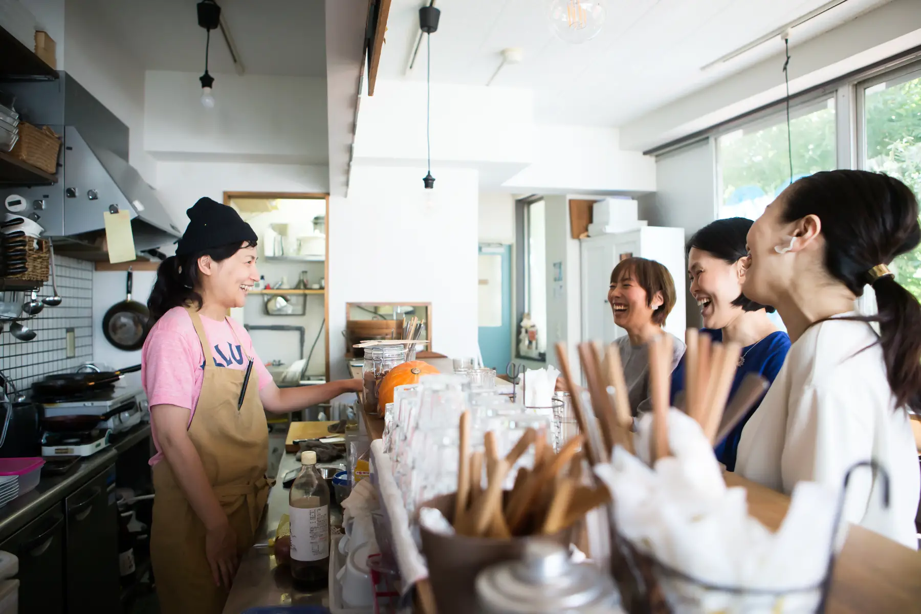 Barista and three female customers laughing together in cafe