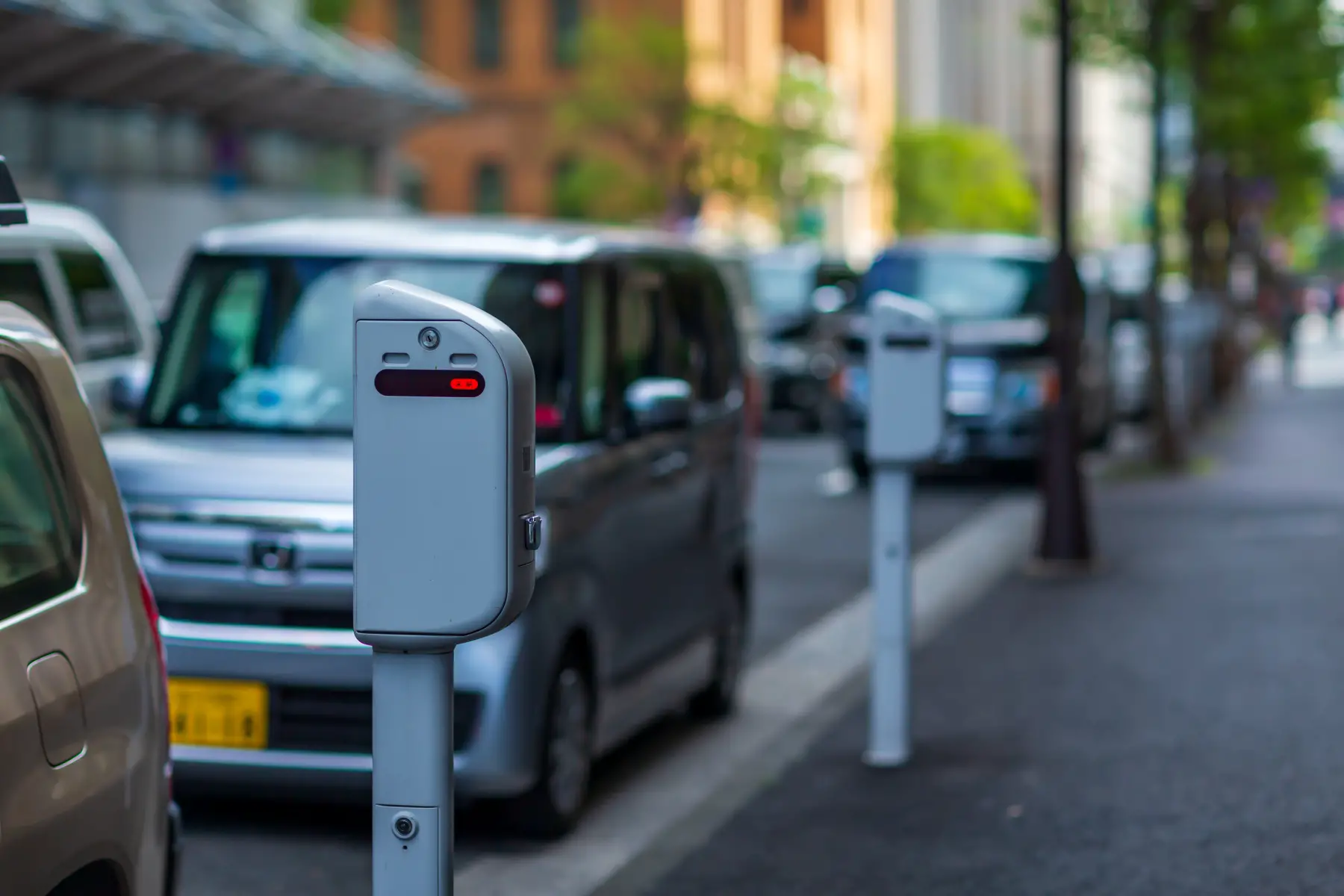 a grey parking meter on the side of a road packed with cars in Tokyo