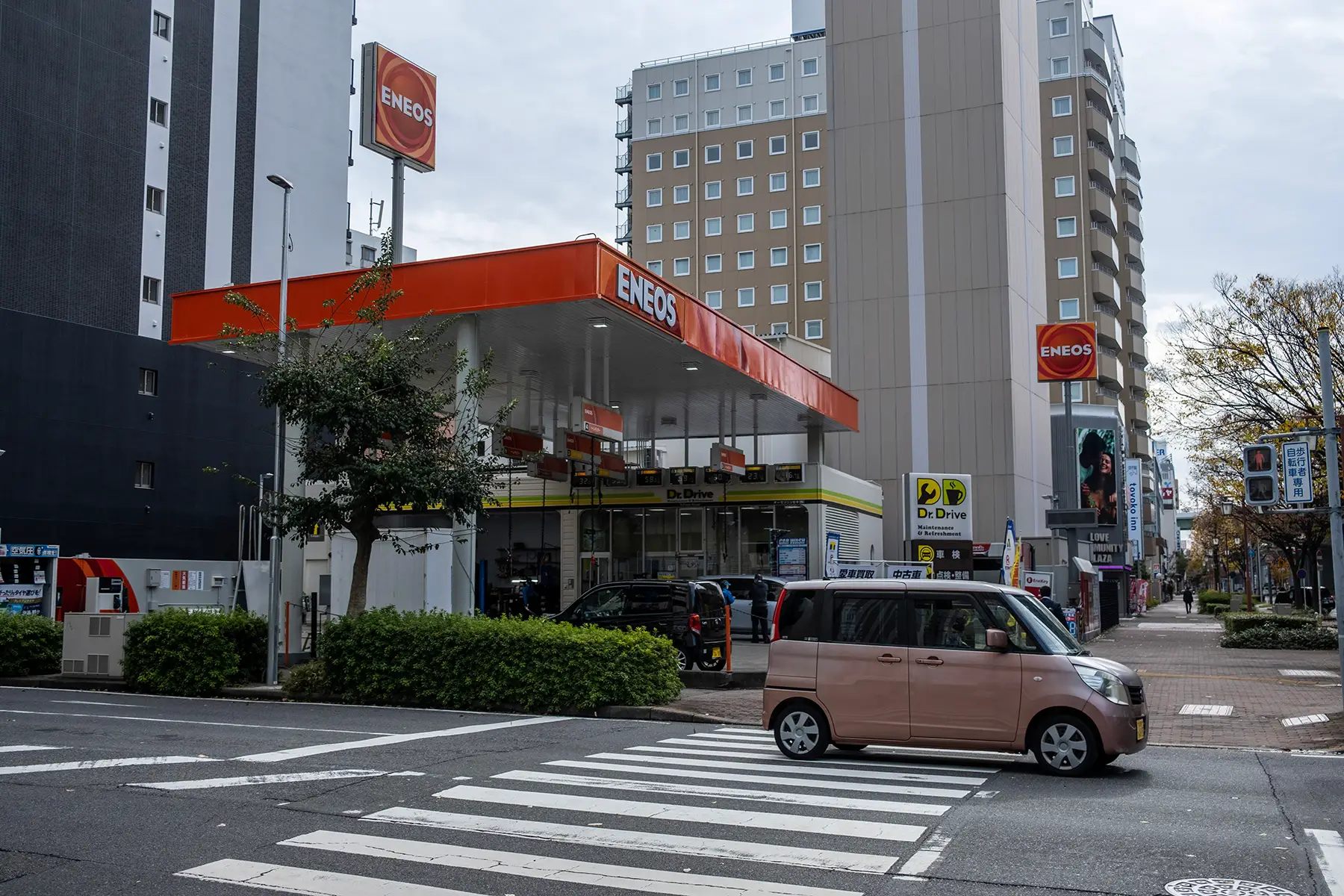 A car driving over a zebra crossing past a petrol station in Nagoya, Japan.