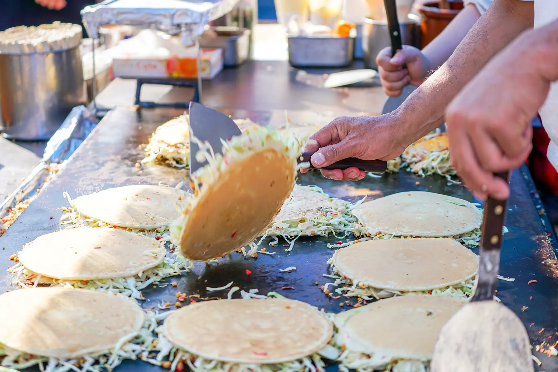 A chef flipping okomiyaki pancake on a hot plate