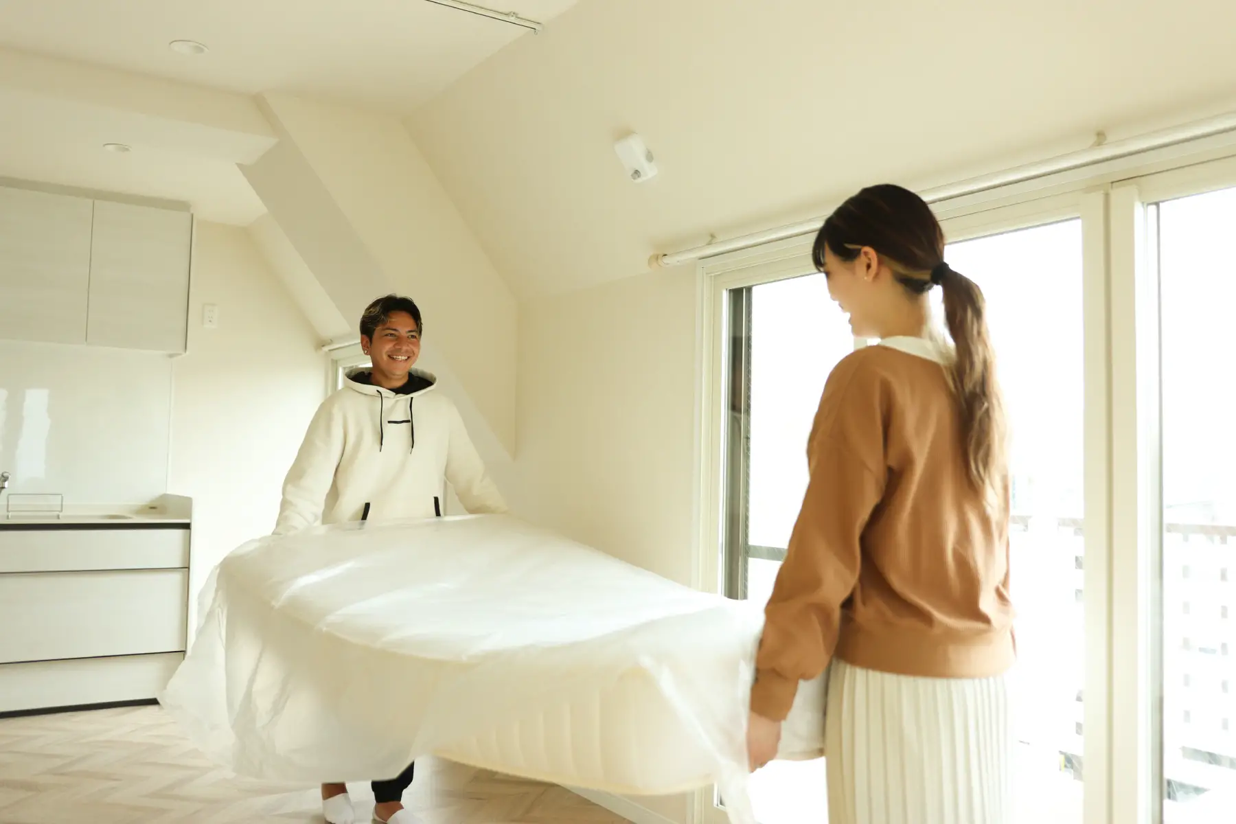 A happy couple move a mattress into a new apartment together