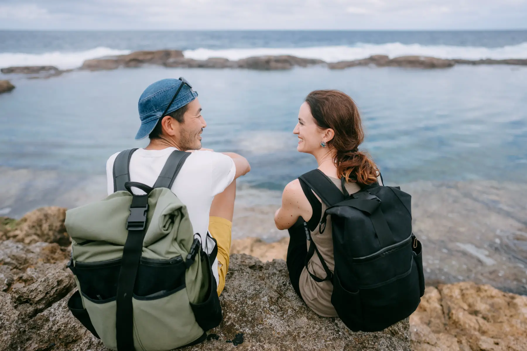 Backpacking couple sitting and smiling at each other at Minami Daito Island, Okinawa
